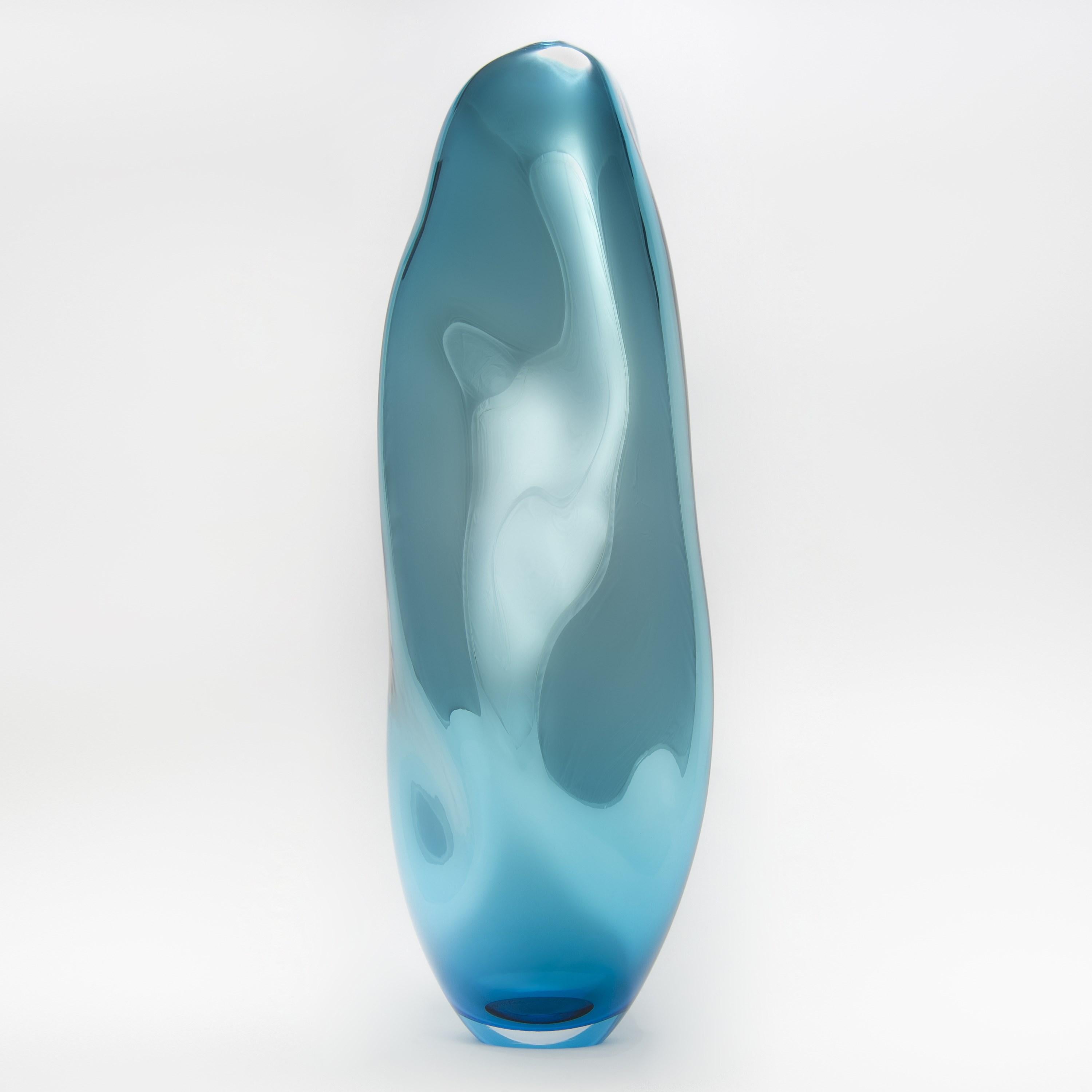 Glass v Metal in Turquoise is a unique handblown sculptural glass vessel created by the British artist Liam Reeves. Handblown in turquoise / aquamarine coloured glass, the interior has a mirrored finish, which results in a beautiful metallic effect.