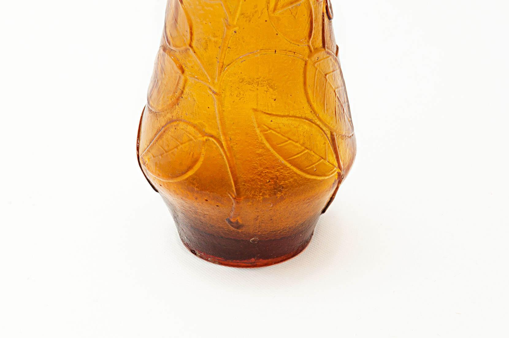 This bottle has been made in the 1960s in Italy, and more precisely the venitian island of Murano.
The decor pattern is donne with flowers carved in the glass, and bubled glass for the bottle cap. This orange color fit very well the a brown wood