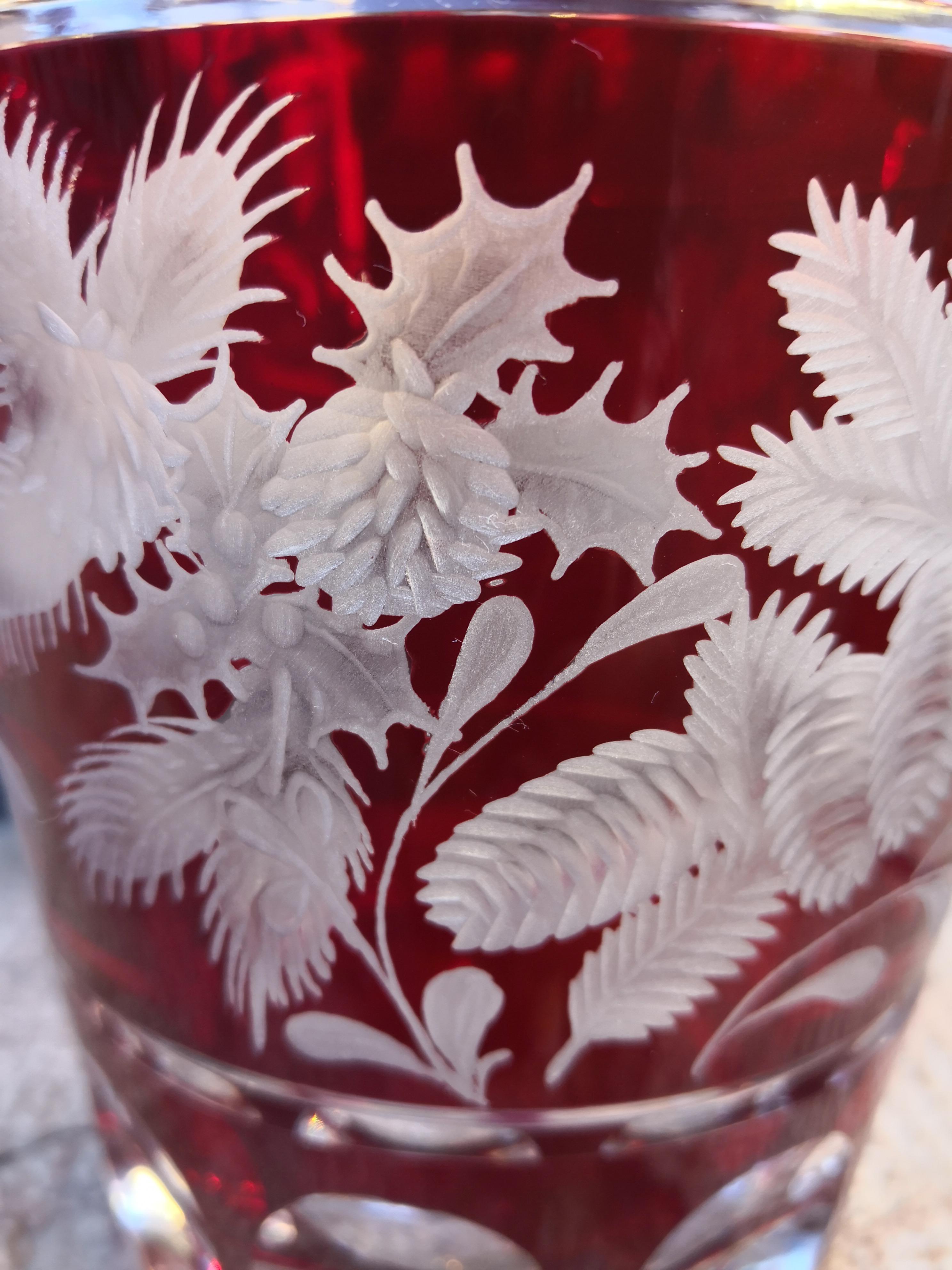 Vase aus mundgeblasenem rotem Kristallglas mit handgeschliffener Weihnachtsgirlande in leuchtender roter Farbe. Die Dekoration besteht aus Stecknadeln und Weihnachtsblumen rundherum. Komplett mundgeblasen und handgraviert in Bayern Deutschland. Das