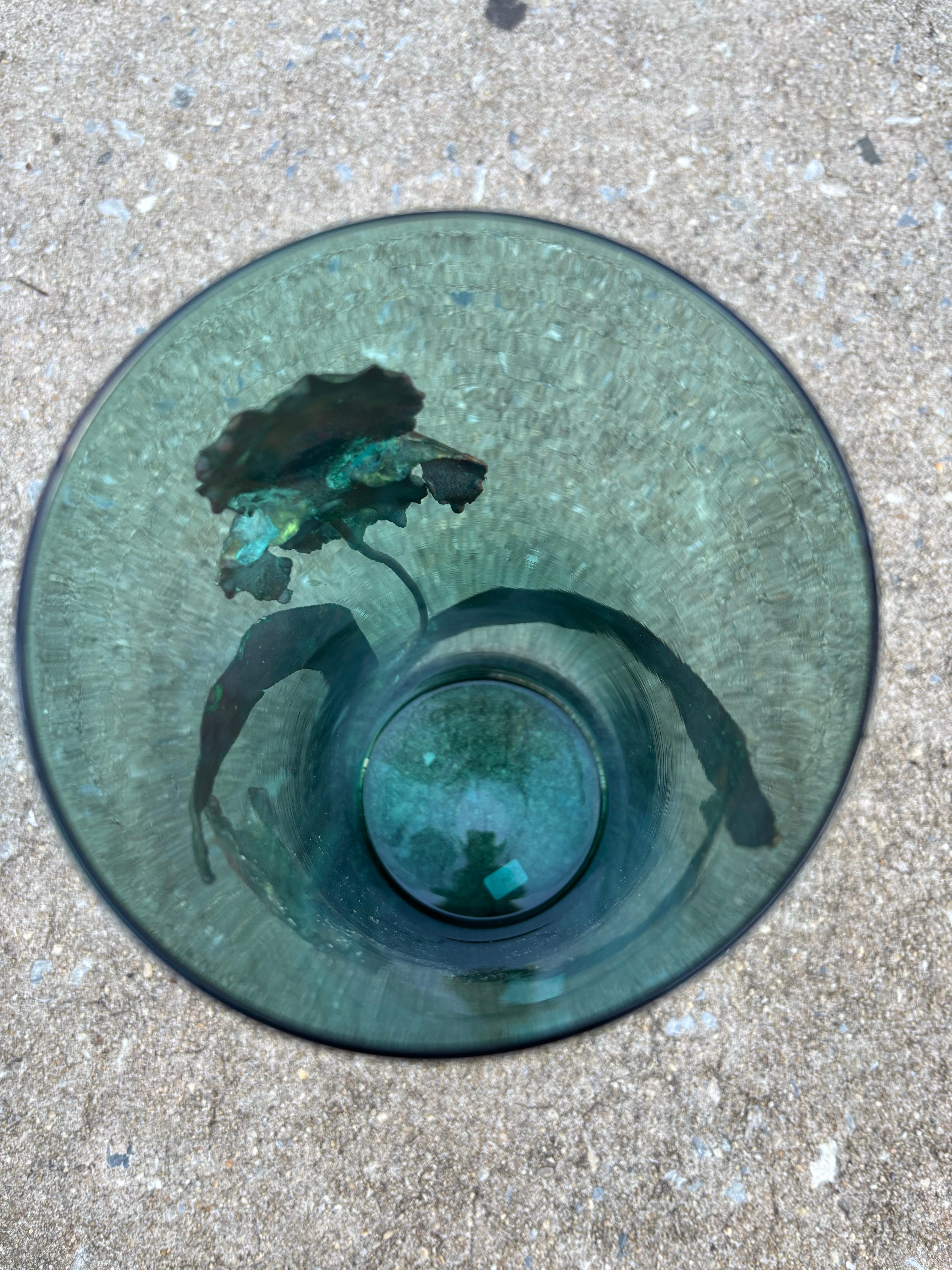Vaso in vetro con gabbia esterna di Iris in metallo.  Foglie e fiori costruiti a mano circondano un vaso di vetro blu/verde.