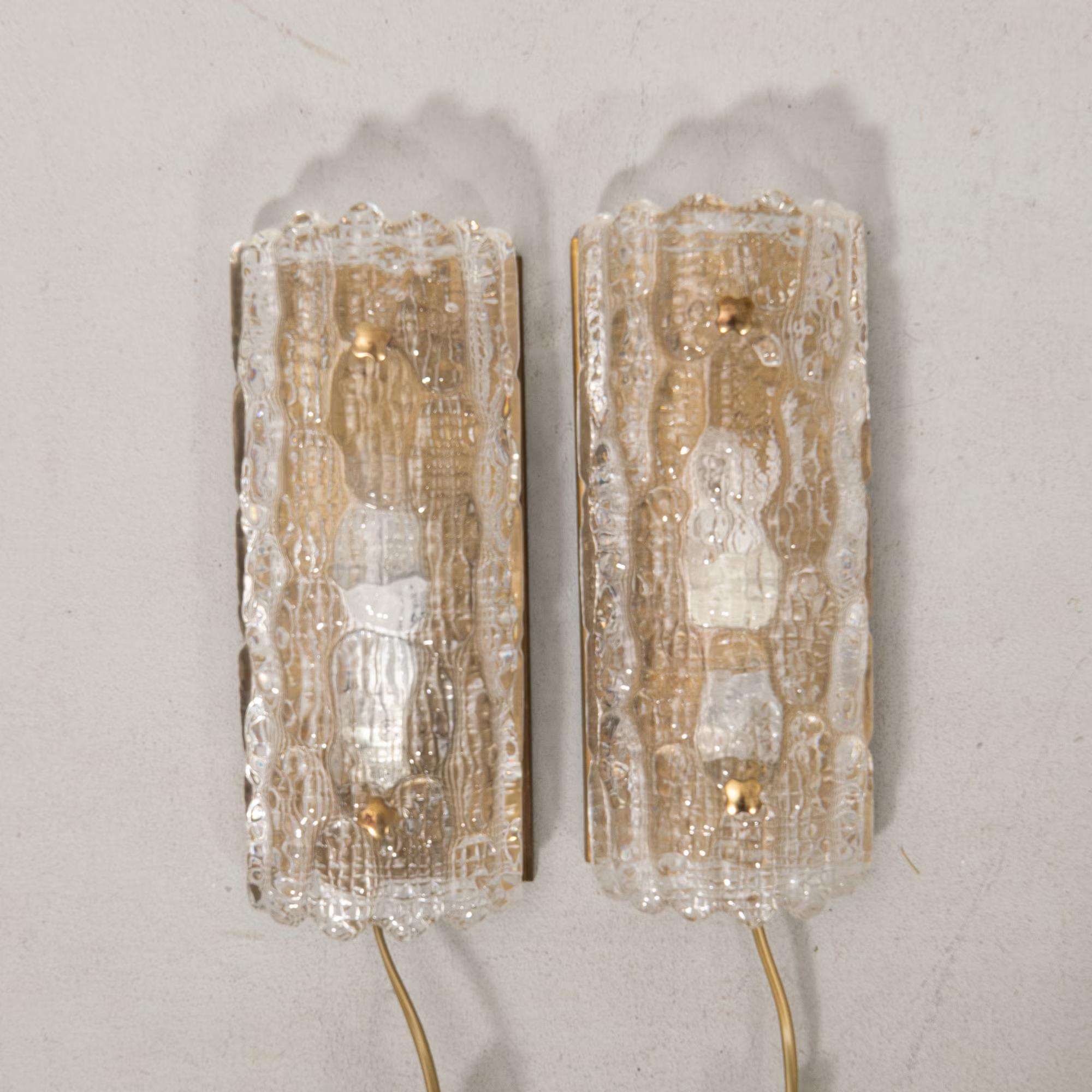 Carl Fagerlund, a pair of wall lamps, made by Orrefors around 1960
Cast glass and brass. For one light source each.
Good vintage overall condition.
Electrical function not tested, can be rewired according to your standards upon request.

2 pairs