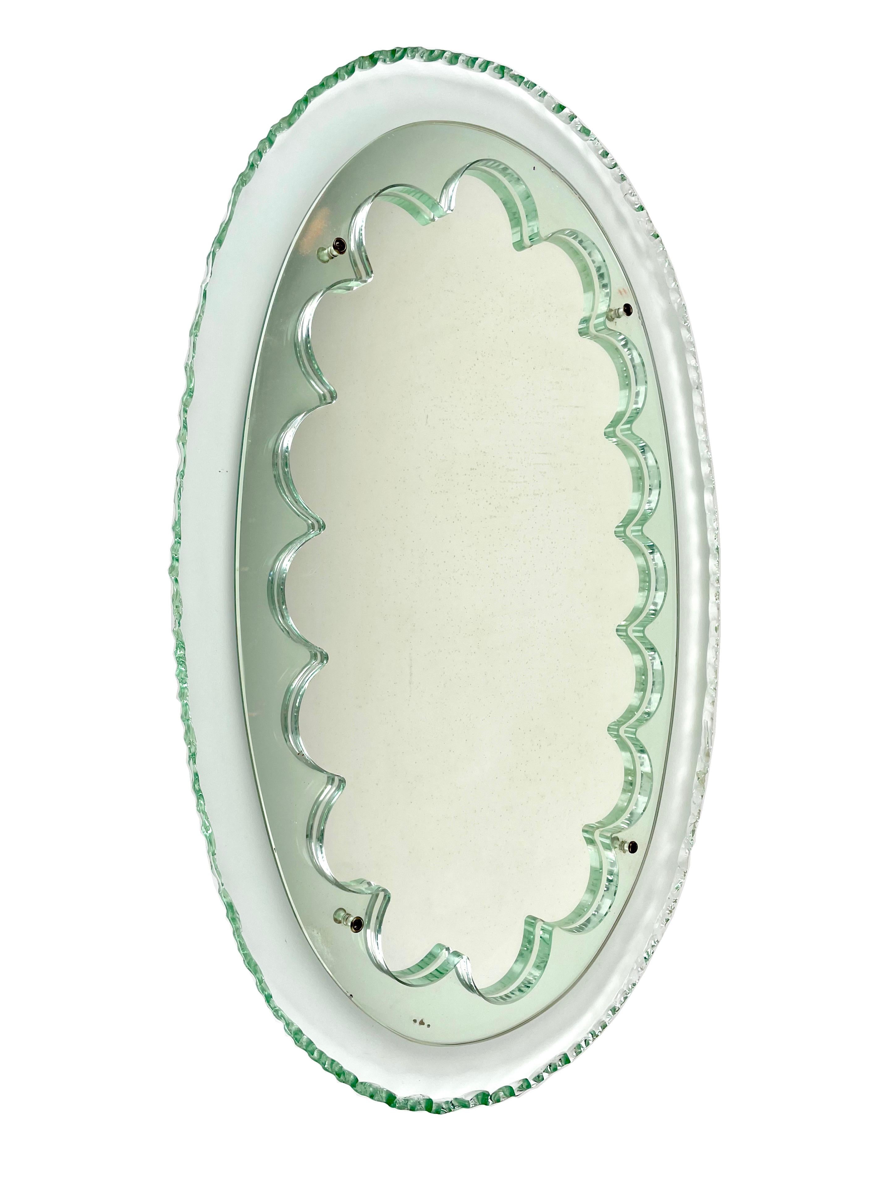 Rare miroir mural en verre vert dans le style de Max Ingrand pour Fontana Arte, Italie, années 1950. 

Forme ovale pour le cadre du verre avec décoration des bords ciselés. Au centre, miroir plat central d'origine serti dans des courbes de verre.