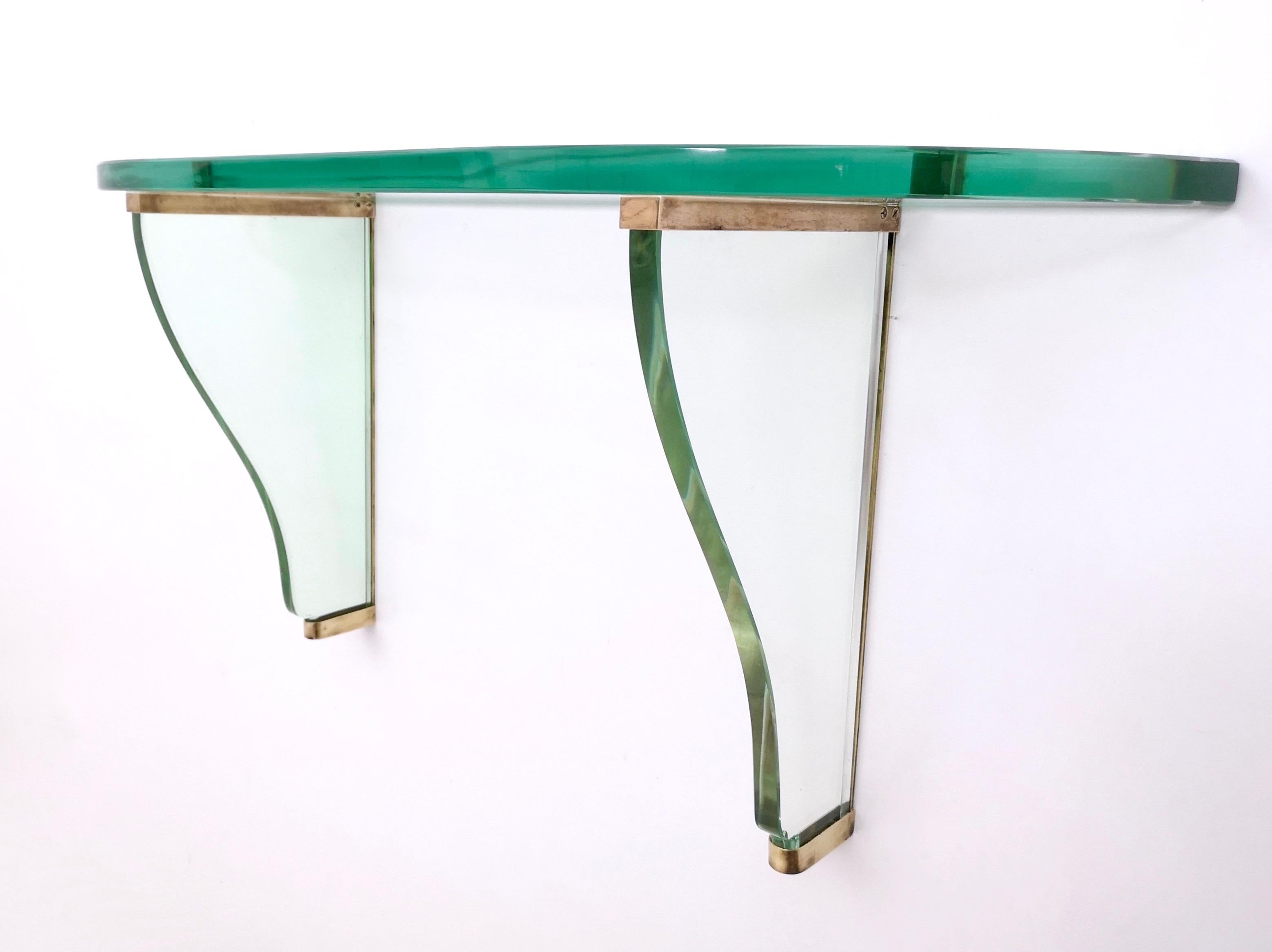 1940s.
This stunning wall-mounted console table features a brass frame and very thick green Nile glass tops and frame.
The originality of this piece is in the color of the glasses, which is extremely rare.
It may show slight traces use since it's