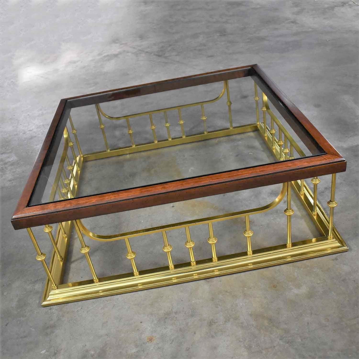 Handsome fireplace fender style brass plated aluminum, glass, and wood large square coffee table attributed to Erwin Lambeth. It is in fabulous vintage condition. There are a few small scratches on the brass plating and a few nicks in the wood frame