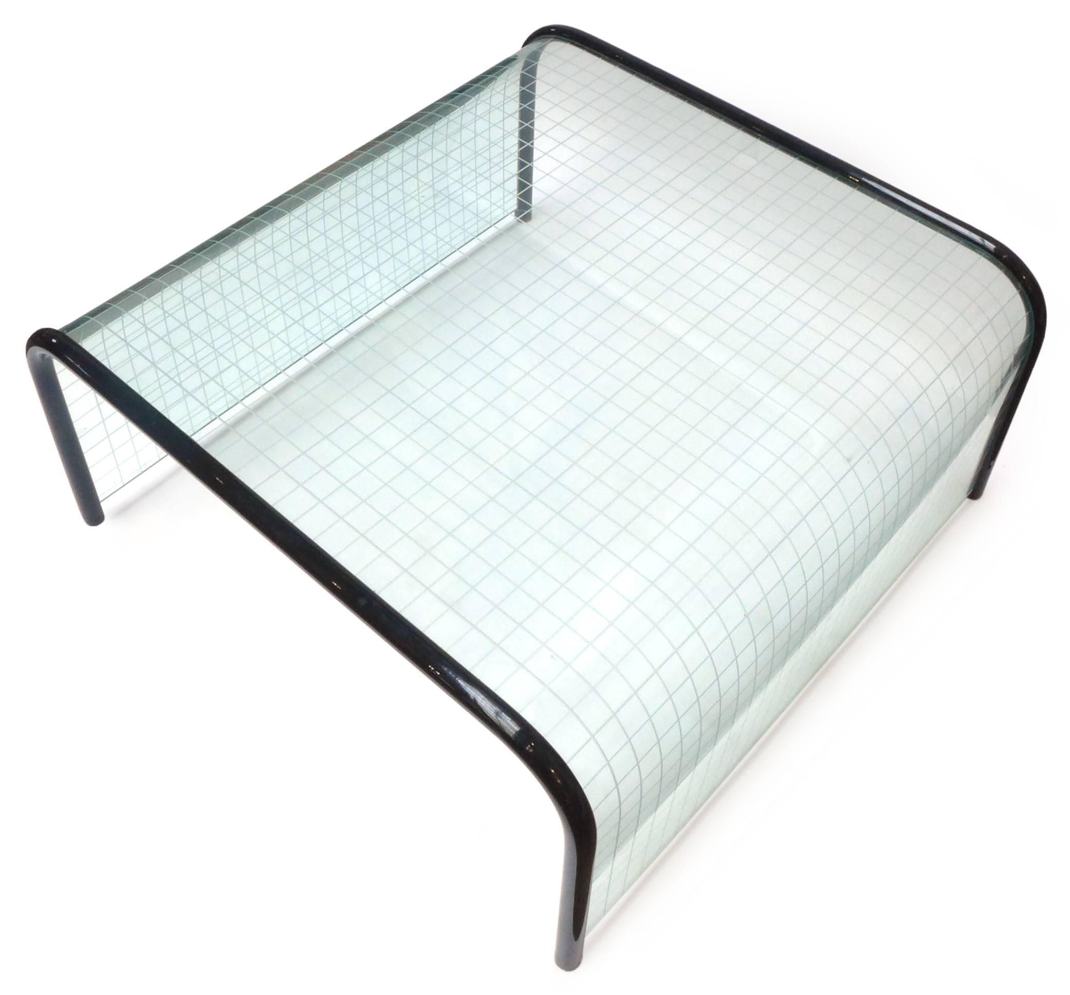 An outstanding waterfall coffee table by Angelo Cortesi for Fiam Italia. A molded glass form with etched grid pattern underneath and thick-gauge, enameled-black, wood-dowel edges. A playful op art effect all around with clear Memphis style and