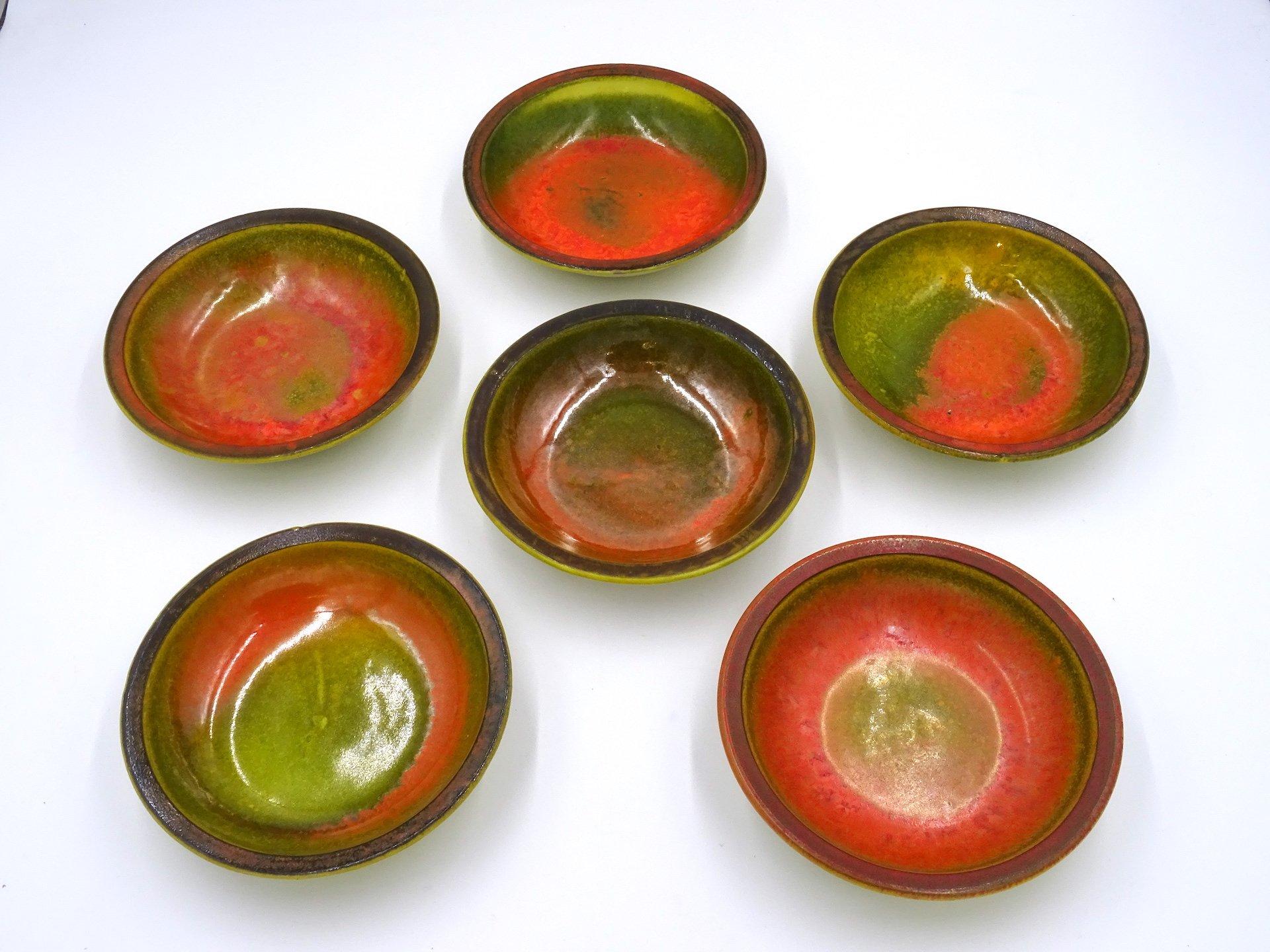 Ensemble composé de sept bols en céramique émaillée polychrome datant des années 70 de l'artiste italien Alessio TASCA :

- six petits bols caractérisés par des couleurs chaudes dont l'orange, le rouge, le vert, le brun, le magenta, chaque pièce