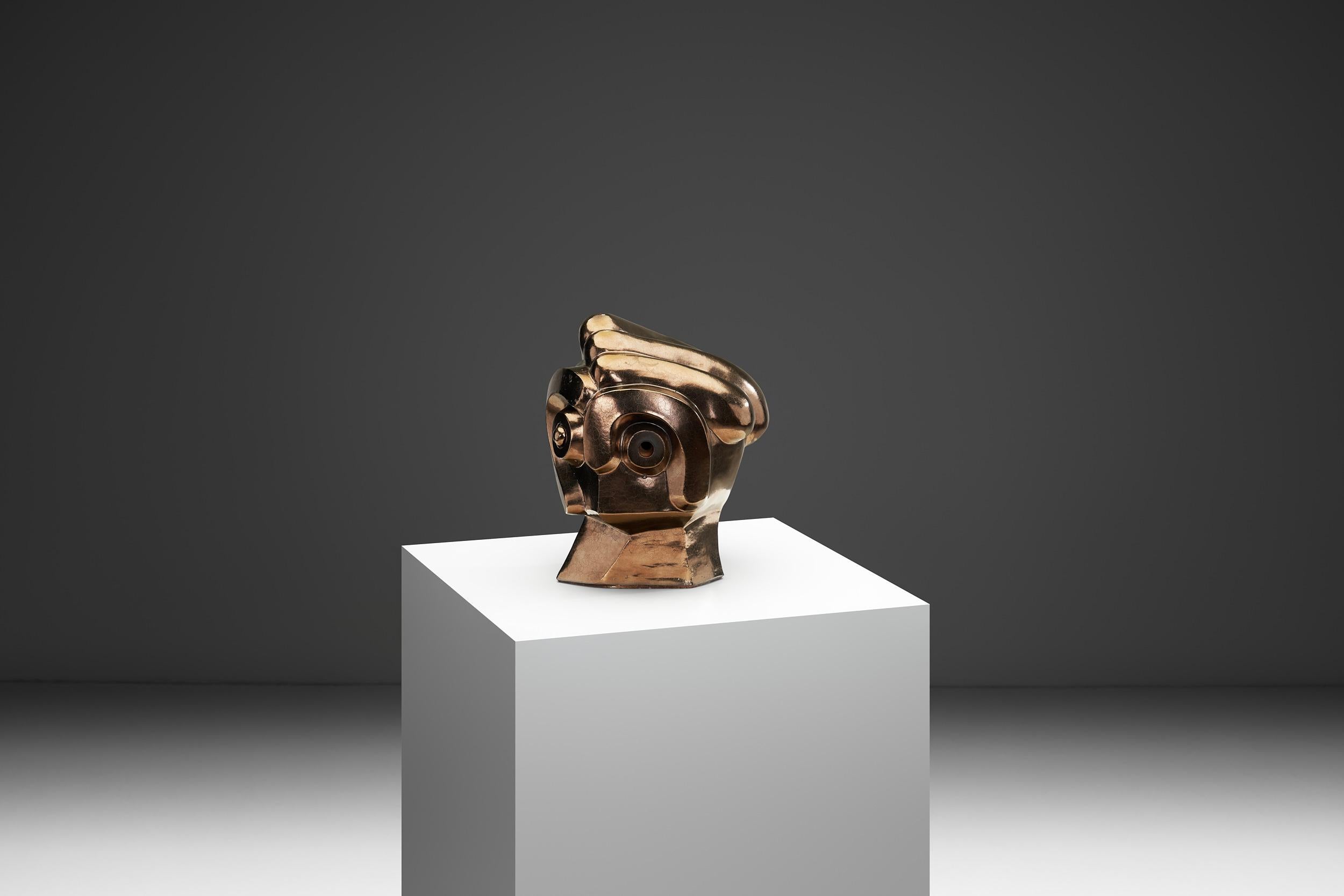 Questa scultura in ceramica presenta una testa umana astratta, realizzata da Roy Terbeek nel 1994 nei Paesi Bassi. Il pezzo presenta una modellazione dei tratti del viso. C'è un senso di armonia nelle proporzioni: il collo è forte ma aggraziato e la