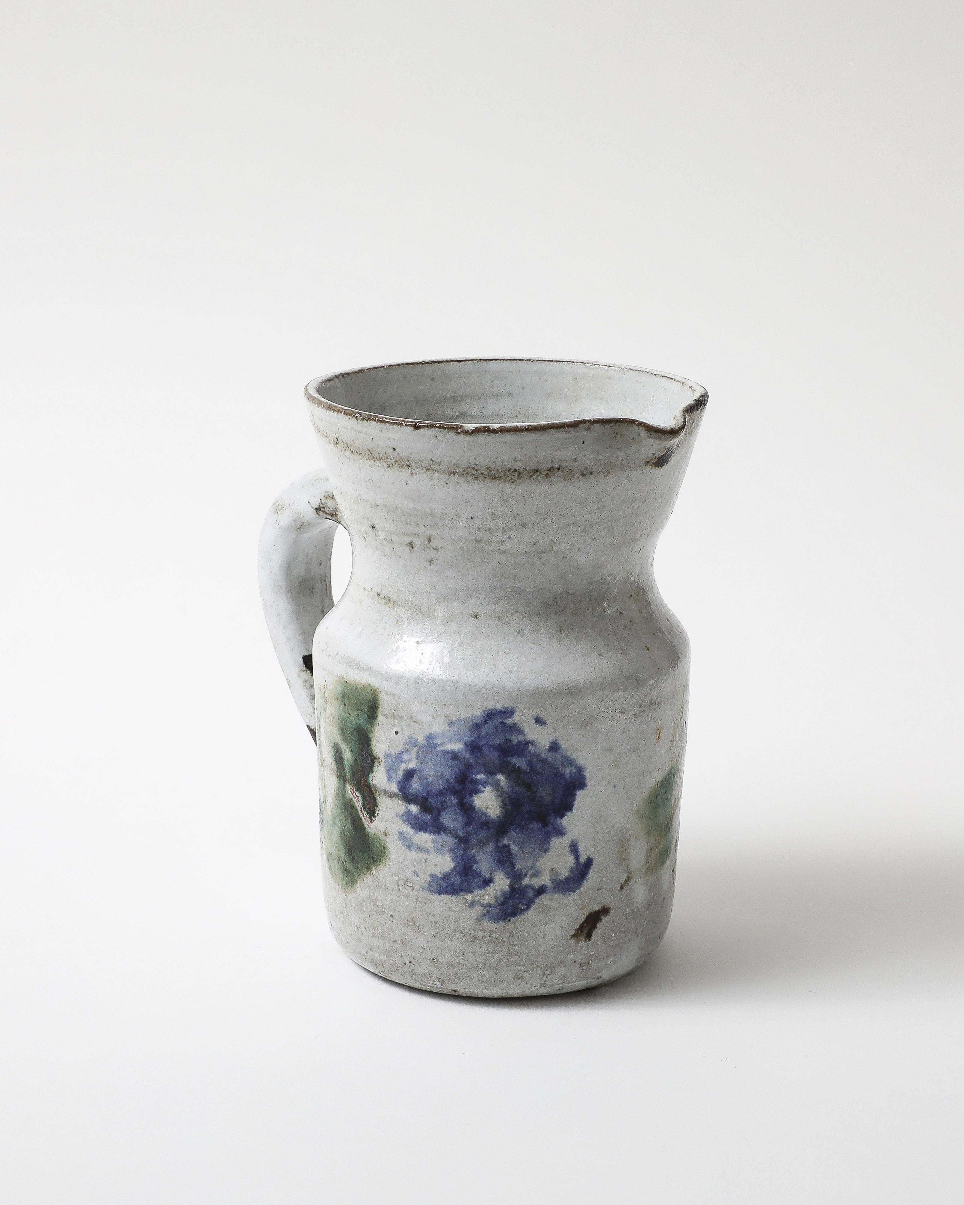 Hand formed and glazed pitcher by celebrate French ceramicist Gustave Reynaud. The design features painted flowers.