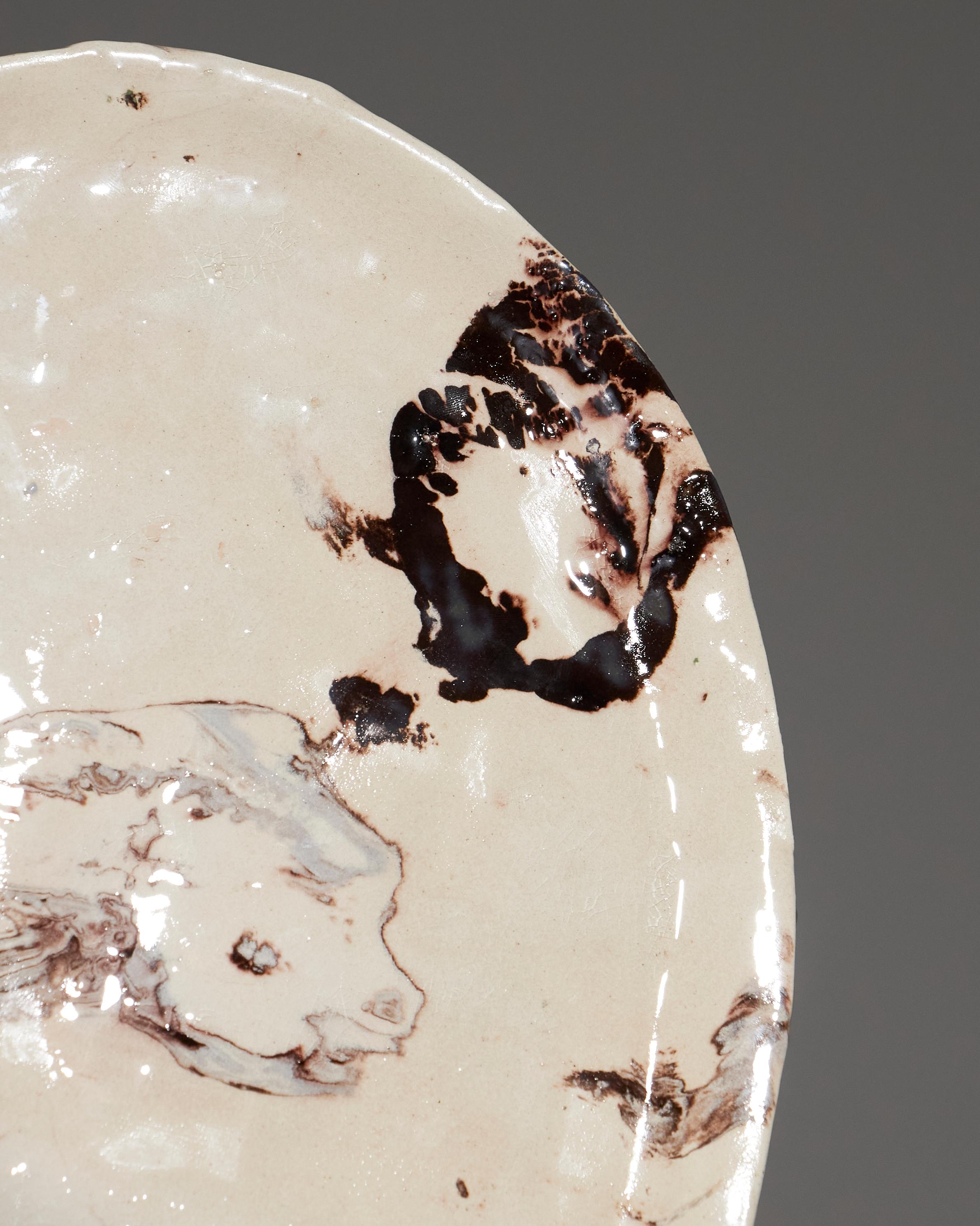 Plat de service en céramique émaillée beige avec effet marbré, par l'artiste Suzie Lapierre d'Artistics. Pièce unique, signée sur la base.
Avec Forma, Suzie Lapierre d'Argy crée des pièces uniques, fabriquées à la main, qui allient la puissance des