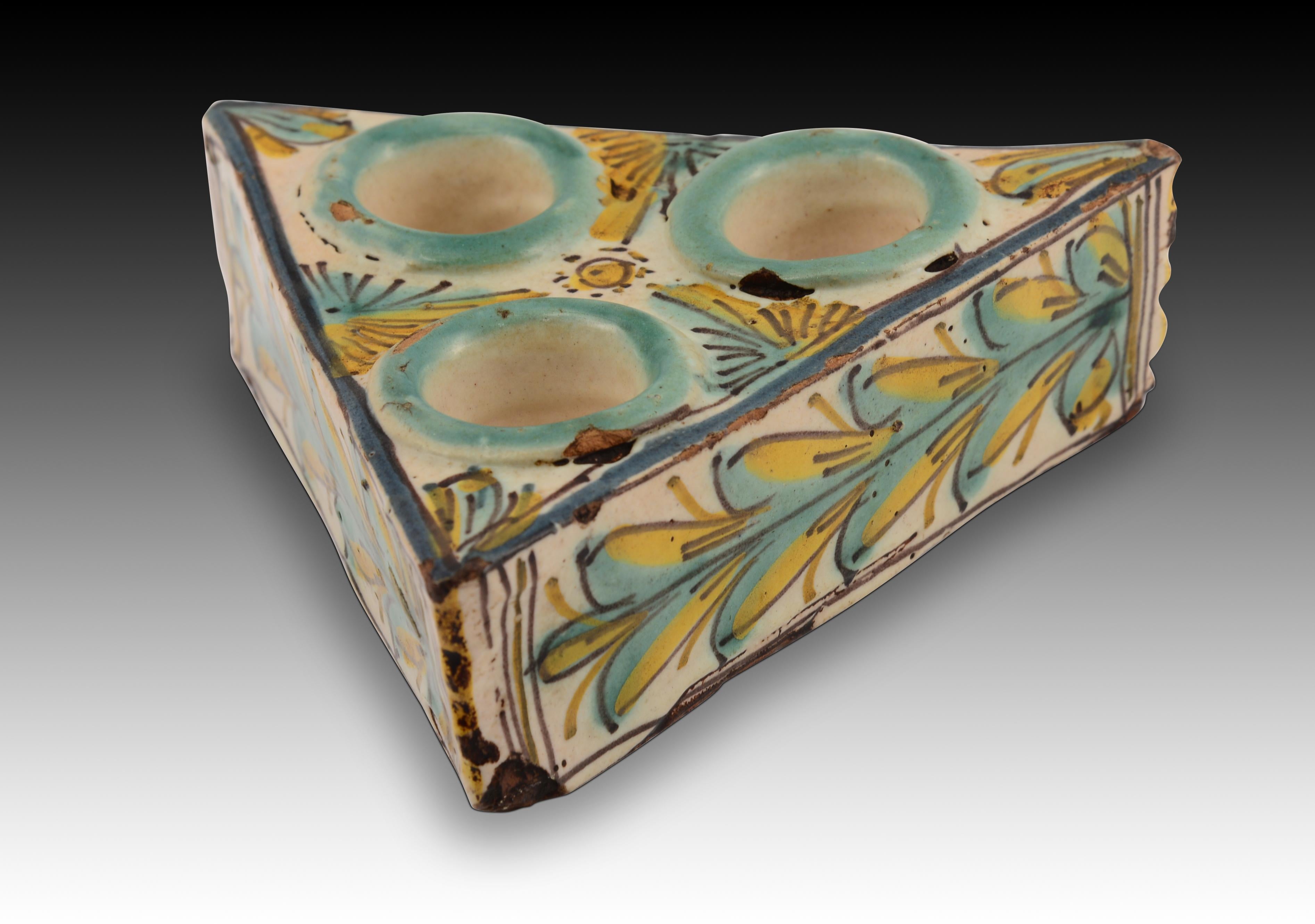 Portaspezie in ceramica smaltata. Talavera de la Reina, XVIII secolo. 
Portaspezie con tre pozzetti a forma di triangolo equilatero, realizzato in ceramica e decorato con smalti ad alta temperatura tipici della policromia Talavera: nero manganese