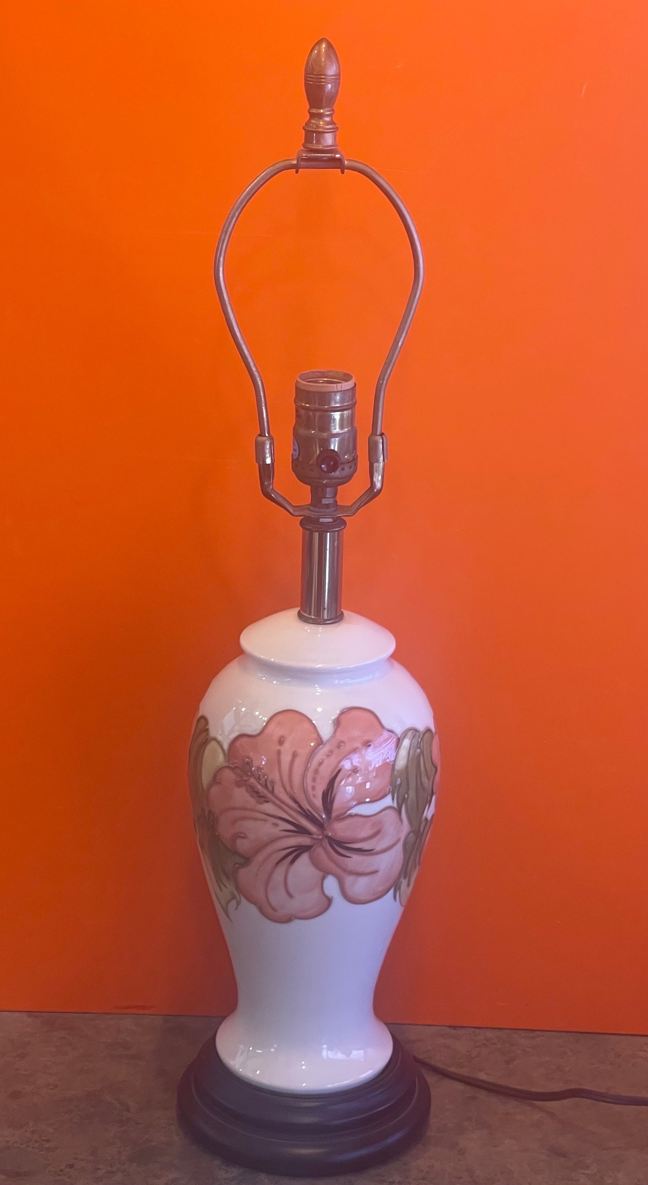 A glazed ceramic studio pottery table lamp with floral motif on walnut base by Moorcroft Pottery, circa 1970s. The lamp measures 5.75