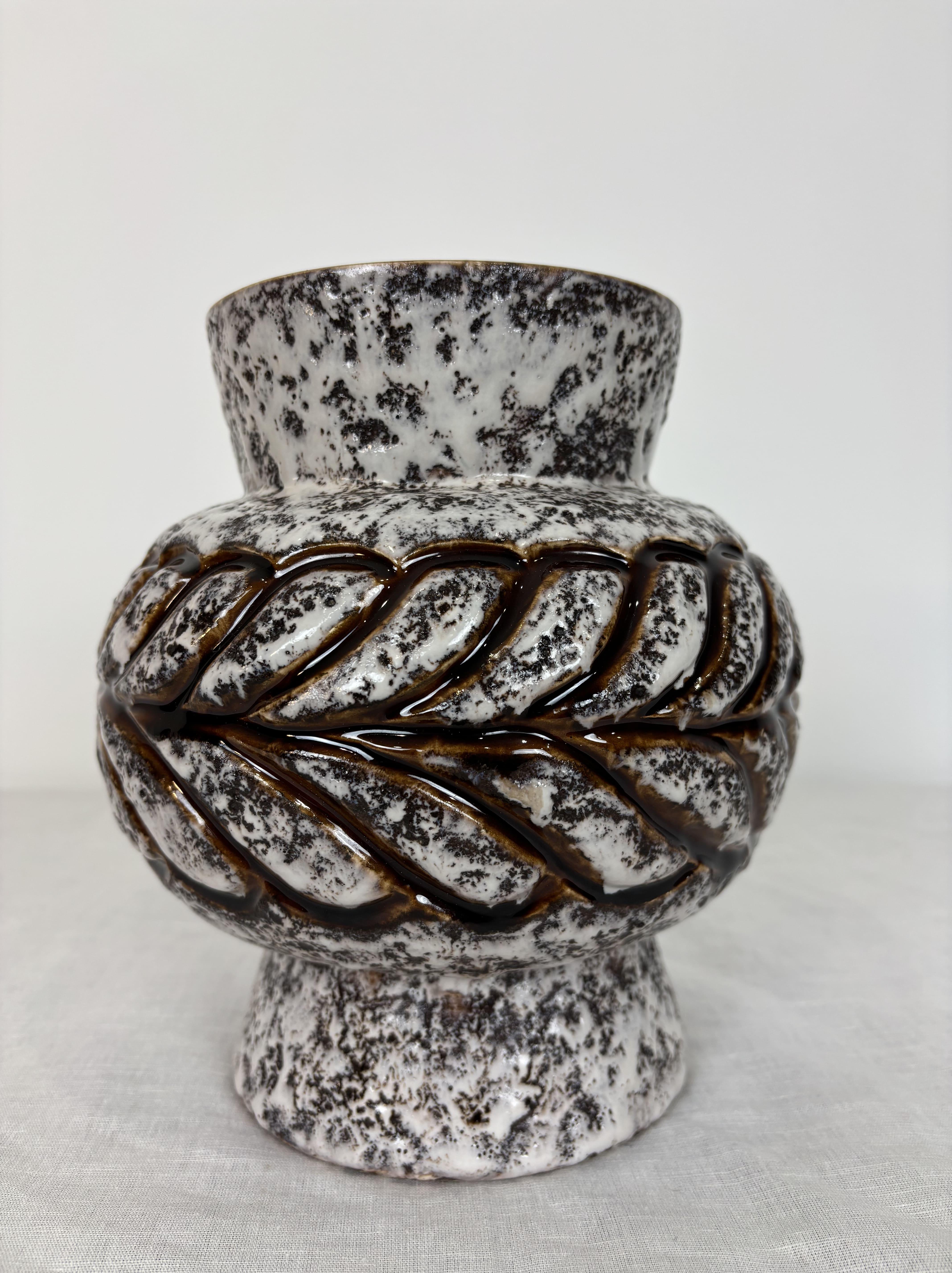 Elegante vaso in gres smaltato bianco e marrone con decorazione a rilievo a treccia stilizzata. 
Tipica ceramica della Germania Occidentale degli anni '60, con una grafica forte e uno smalto maculato molto strutturato. 
L'interno è smaltato in un