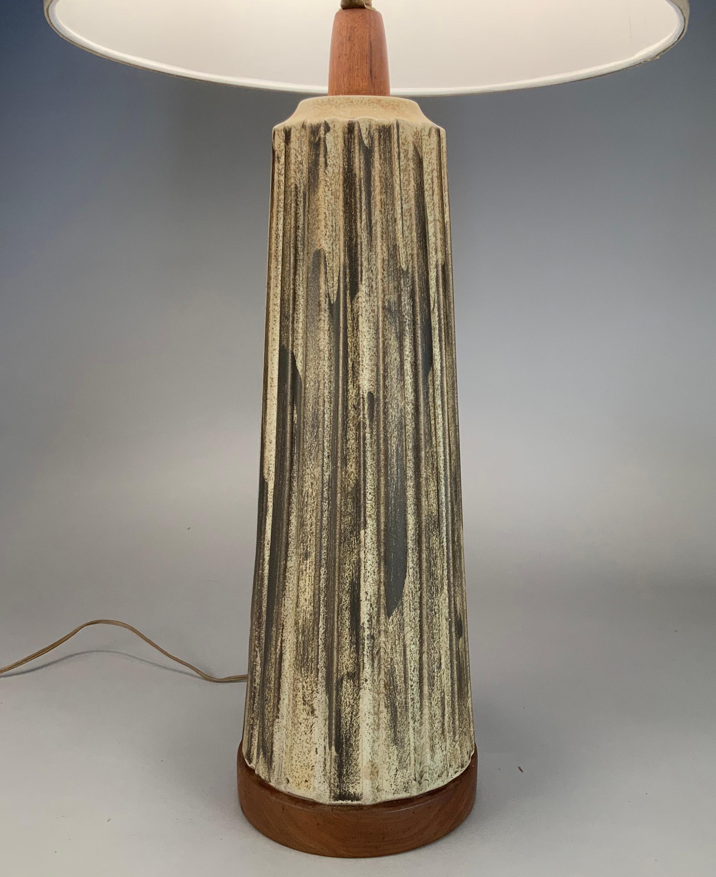 A beautiful and impressive 1950's ceramic lamp with walnut base and stem by Gordon Martz. The tapered lamp with a scalloped surface, finished and glazed in shades of cream and charcoal gray. Mint condition.