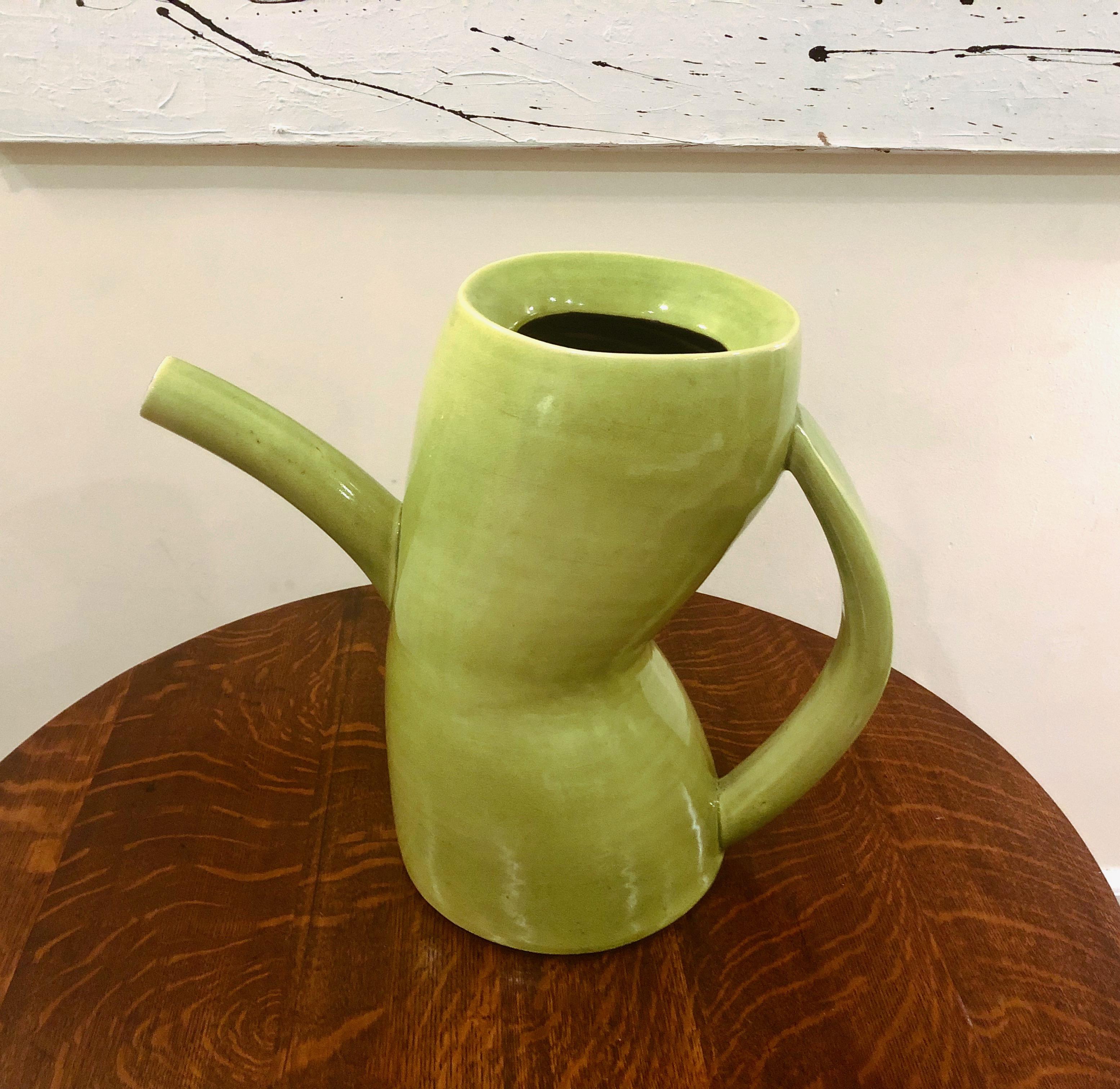 Chartreuse colored glazed ceramic watering pitcher sculpture made by artist and professor Jamie Walker in 1990 with a crackled exterior finish, and angled body, a black, ribbed structured interior in the center opening and a glazed black finish in