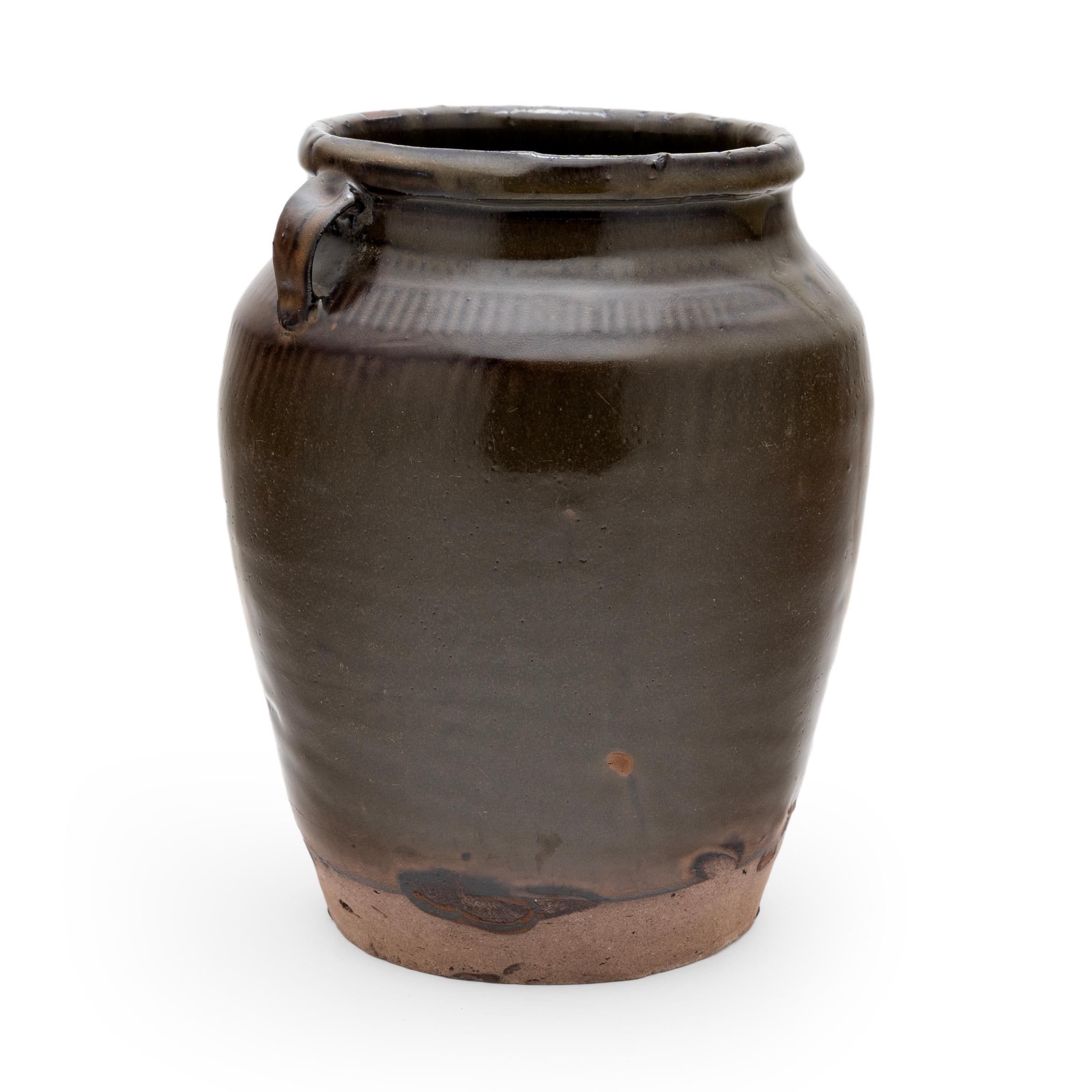 Originally used to store foods or pickle vegetables in a provincial Chinese kitchen, this late 19th-century ceramic jar is coated inside and out with a richly-colored matte brown glaze. The thick glaze drips down the sides, allowing the ripples of