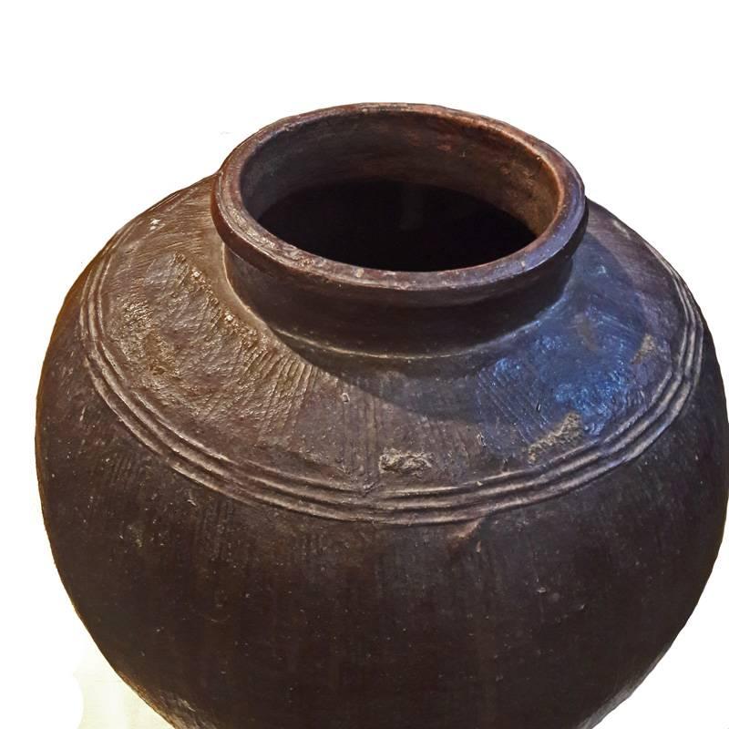 A clay jar glazed in brown from India. Handmade.