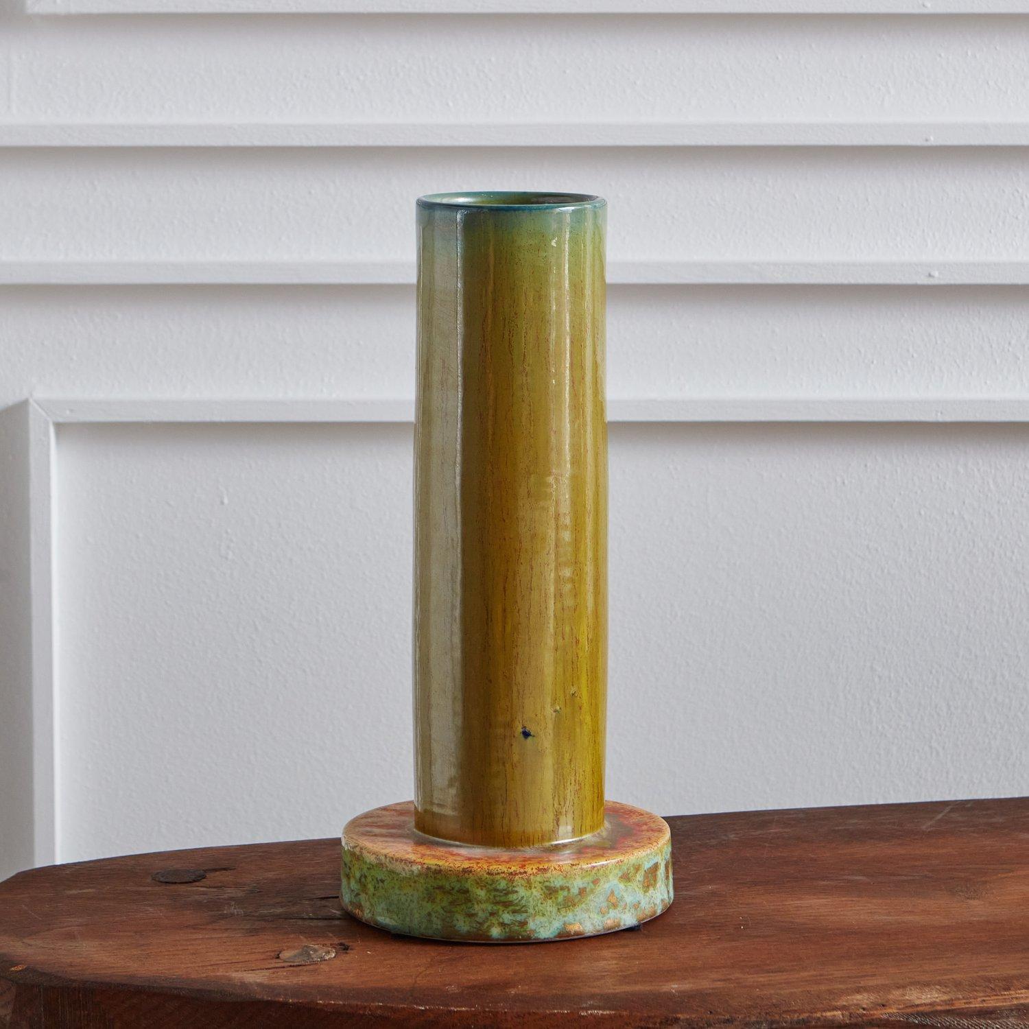 A handmade green glazed ceramic vase sourced in Italy. This vase has a circular base and a tall conical body with beautiful green, blue and orange hues. Signed “CM 2004 Made in Italy.”