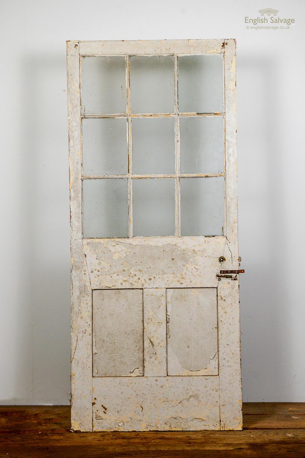 Salvaged 9 glazed panel pine door with two panels below. Painted cream with flaking and peeling. Glazed panels are intact.