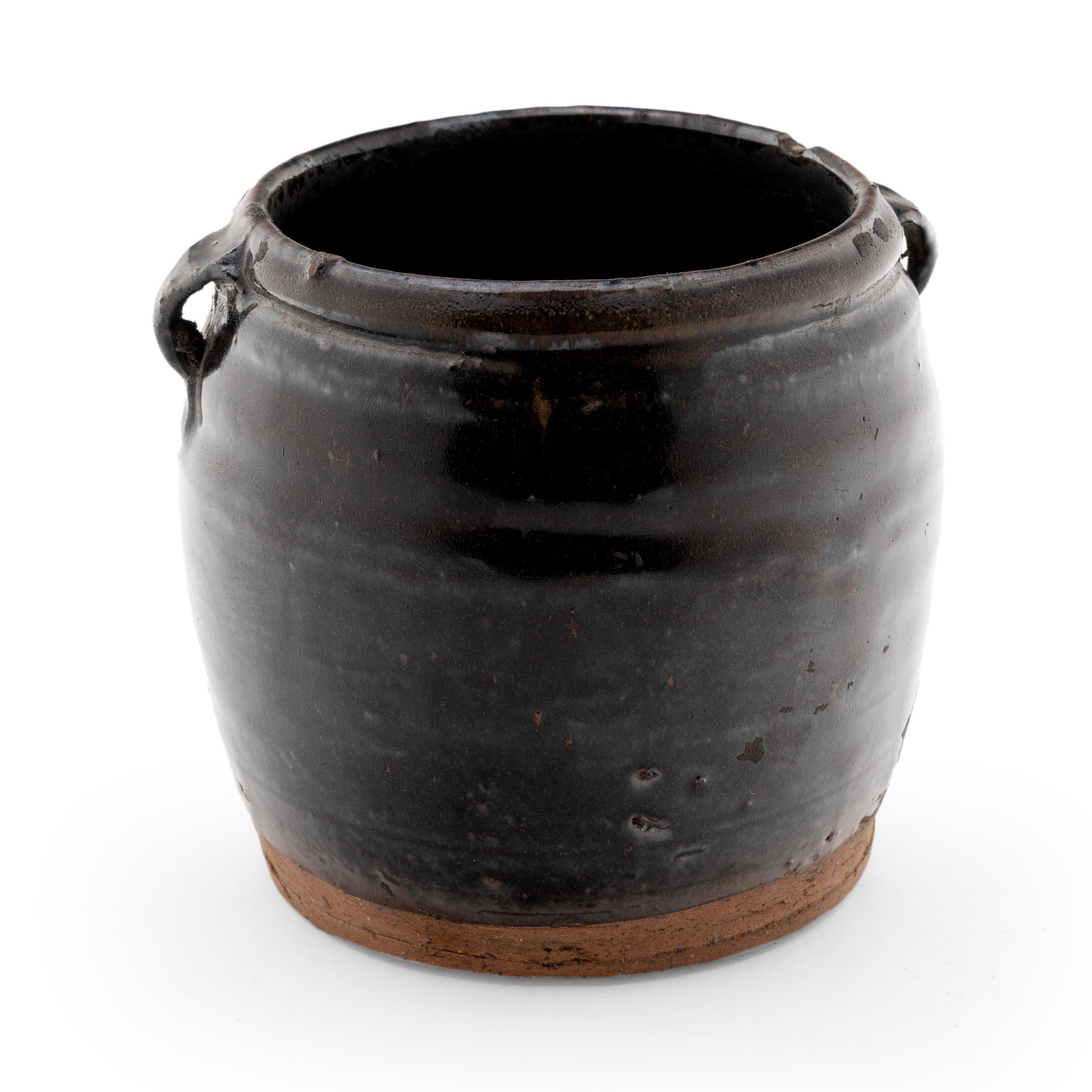 A thick brown glaze coats the stout body of this early 20th century terra cotta kitchen jar. As evidenced by the glazed interior, this wide-mouth jar was once used daily in a Provincial Chinese kitchen for fermenting foods and condiments. The