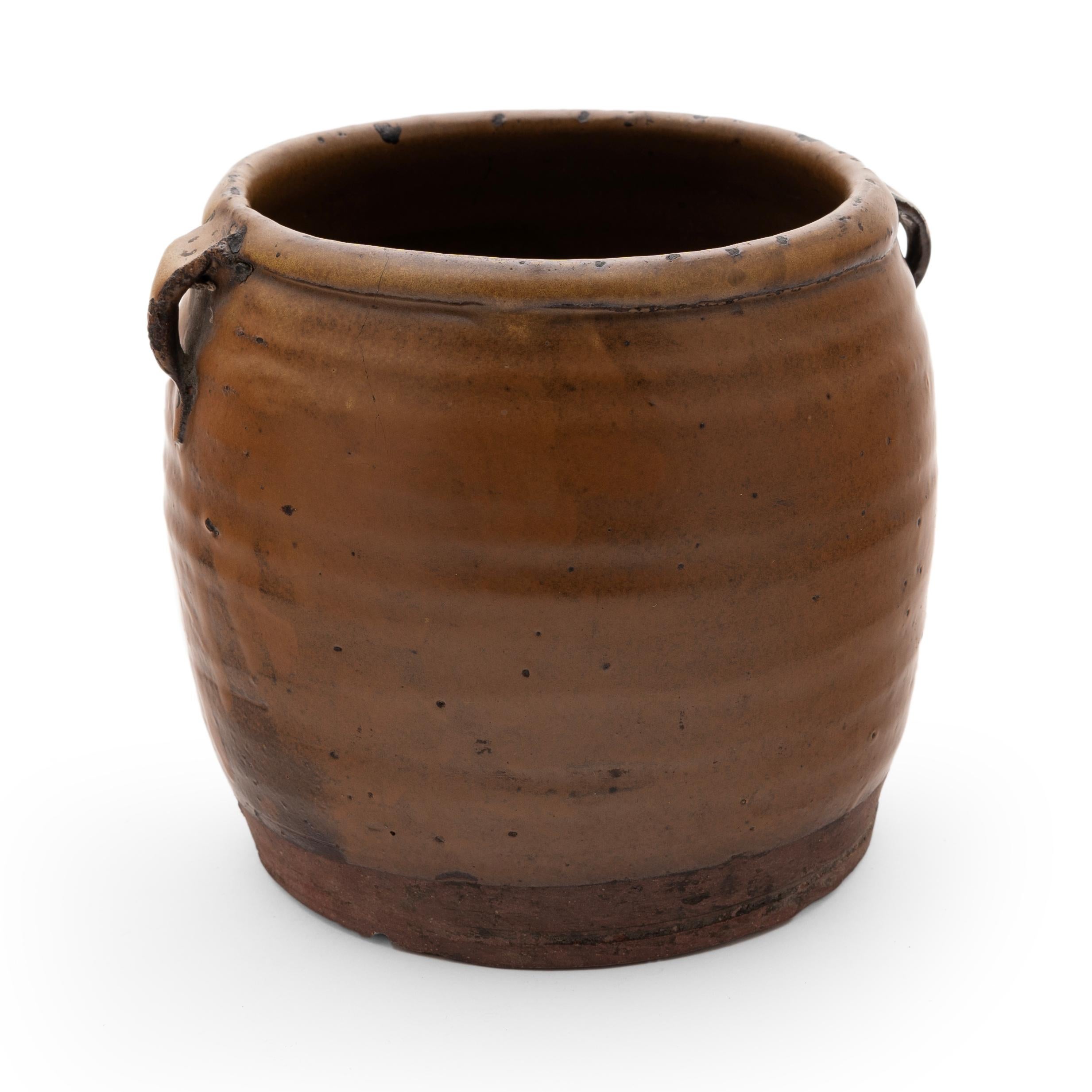 A thick, light brown glaze coats the stout body of this early 20th century terra cotta kitchen jar. As evidenced by the glazed interior, this wide-mouth jar was once used daily in a Provincial Chinese kitchen for fermenting foods and condiments. The