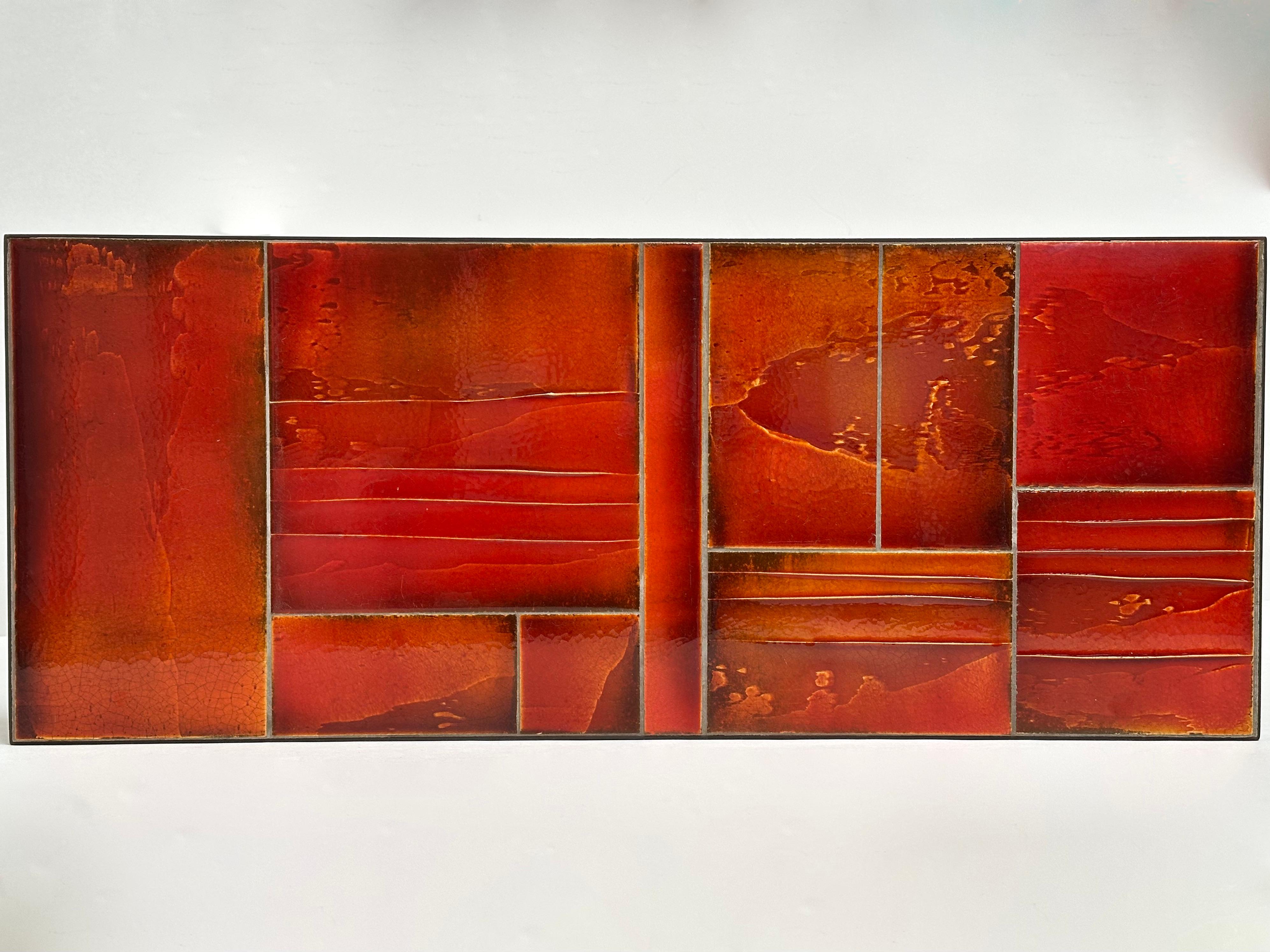 Table basse composée d'un plateau de plaques de lave engobées émaillées dans une gamme de rouge orangé transparent, monté sur une structure en acier brossé.
Signature de l'Artistics sous l'émail.

Cette table spectaculaire est présentée dans sa