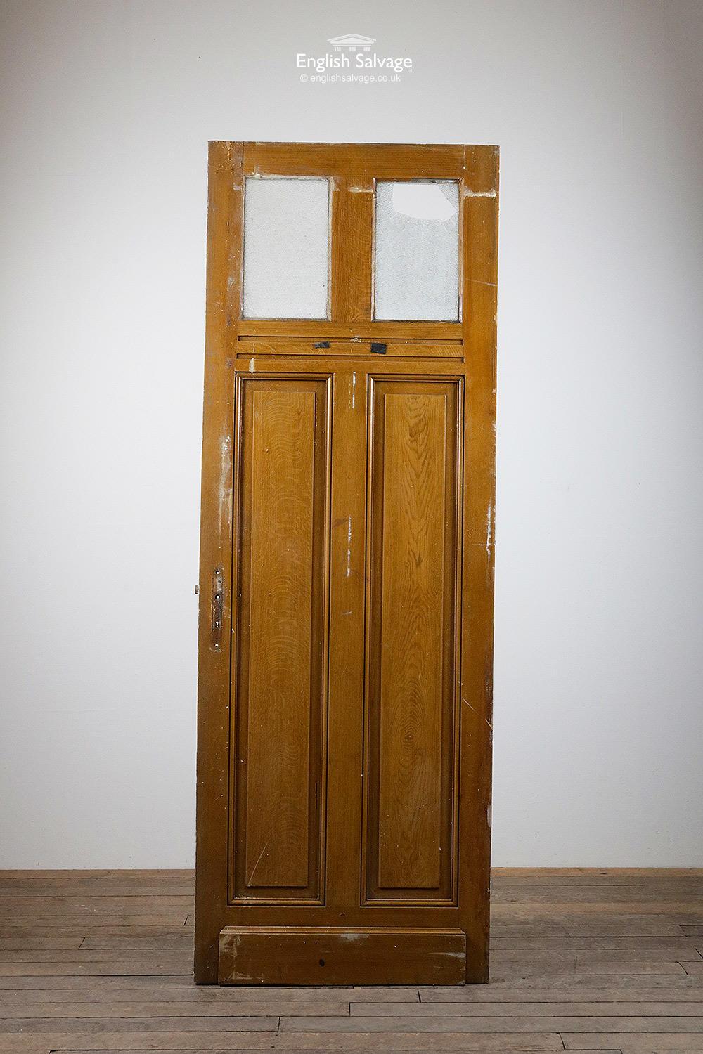 Reclaimed glazed pine door with two small textured glass panels (one broken) over two raised and fielded lower panels. Three hinges. One side oak effect stain, other side painted white with pink beading.