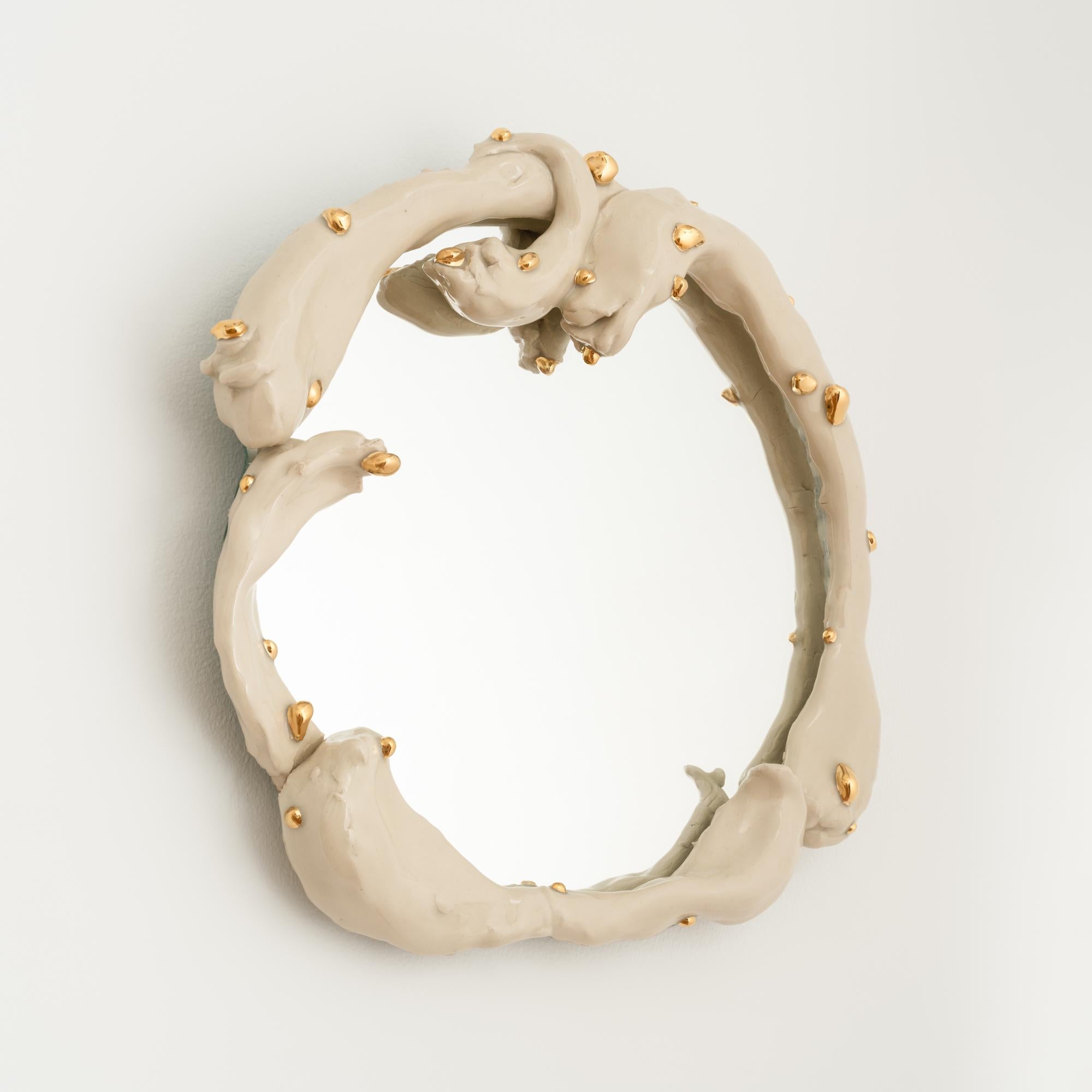 This one-of-a-kind wall circular mirror features a hand-built stoneware frame finished in a glossy cream-colored glaze and embellished with blob-like applications of 22k gold luster. 

Both functional and visually striking, this ornate and