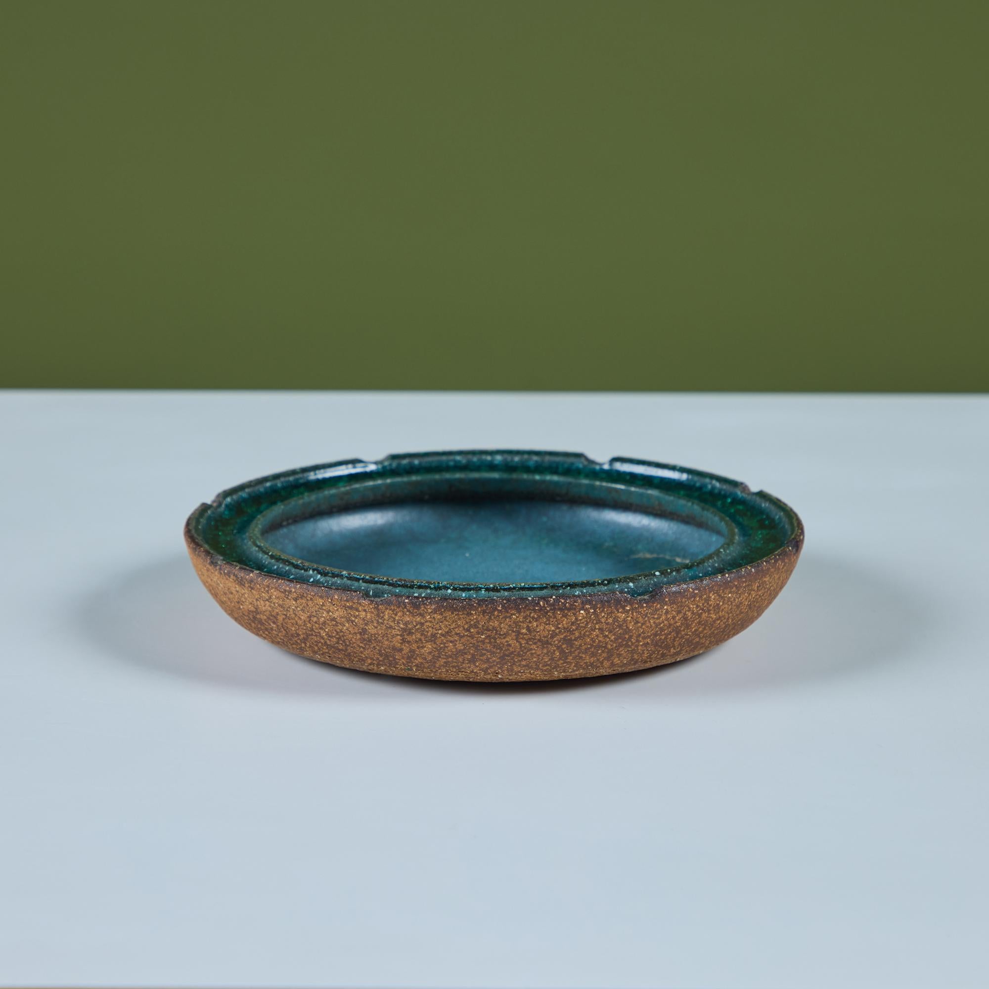 Cendrier en grès avec bord incrusté de verre. Le cendrier rond présente un extérieur et un dessous non émaillés avec un bord en verre vert brillant écrasé et un intérieur émaillé turquoise. L'œuvre est signée par l'artiste sur la face