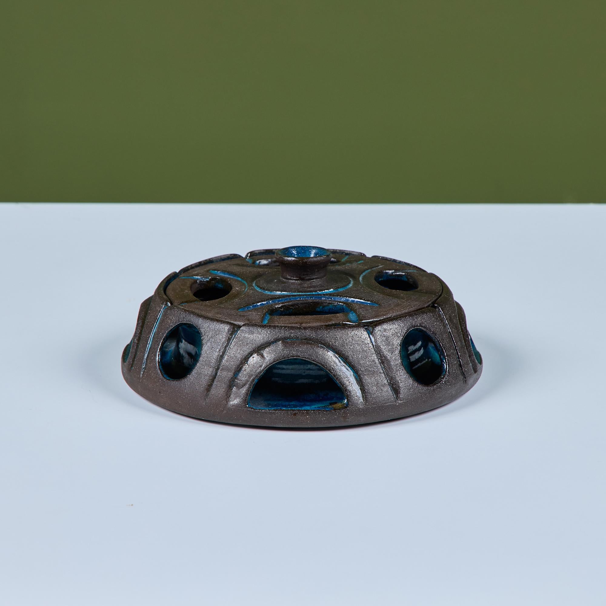 Studio ceramic lidded bowl with a high gloss blue interior and dark brown exterior. Both the lid and bowl showcase circular cutouts and incised linear blue details. Could be a fun catchall or incense cone holder.

Dimensioni
7.75