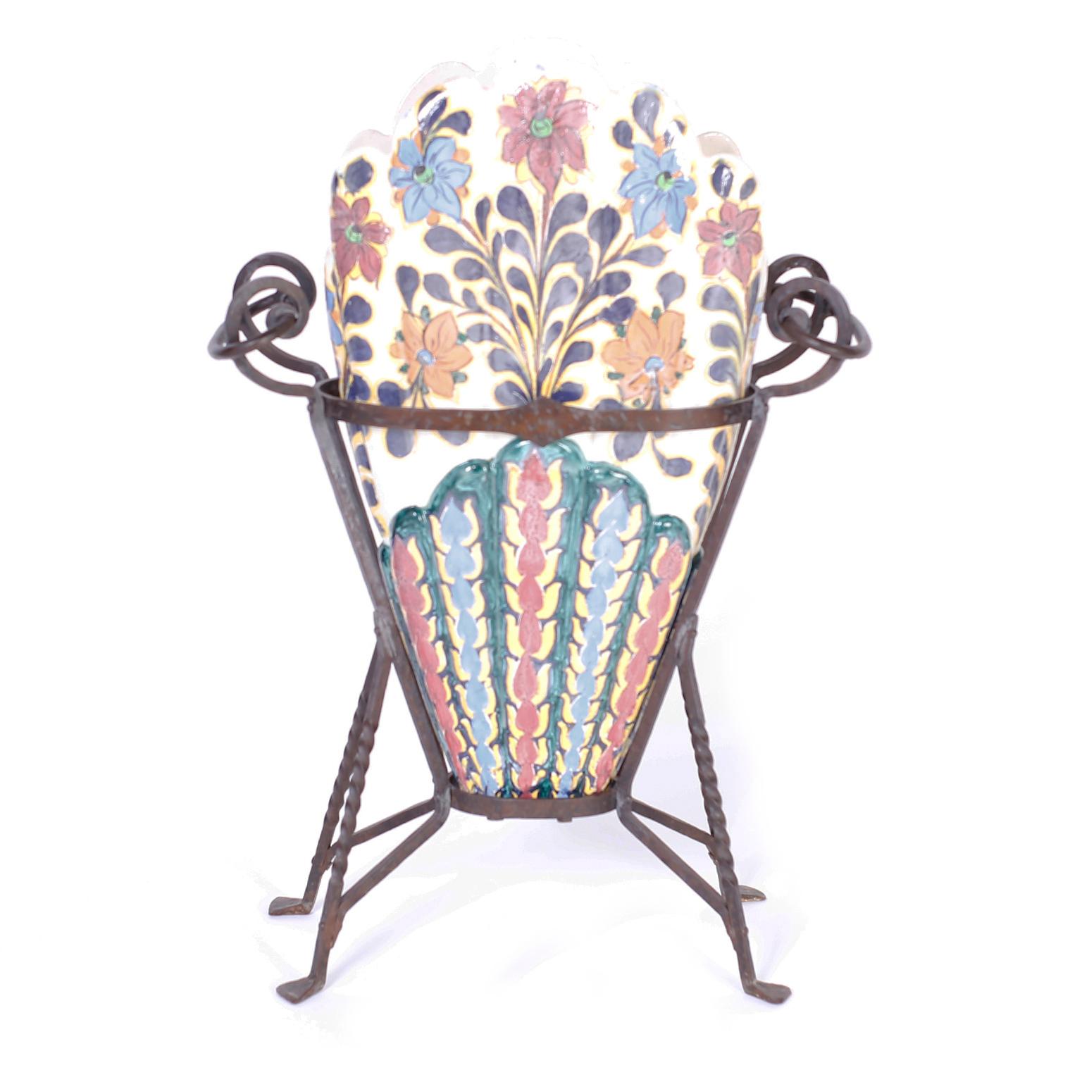 Italian umbrella stand crafted in terra cotta, decorated with flowers and glazed with three compartments and set in a hand wrought iron stand with dramatic handles.