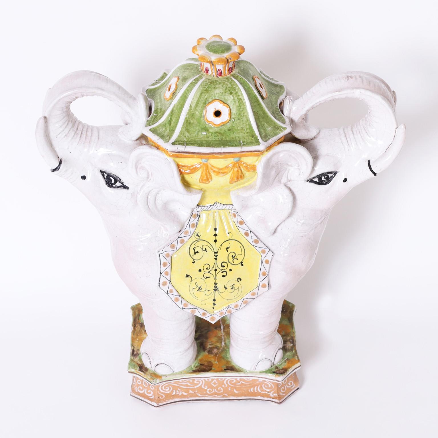 Whimsical mid century Italian glazed earthenware stand decorated with distinctive Mediterranean colors over a dramatic double elephant form supporting a lidded urn.