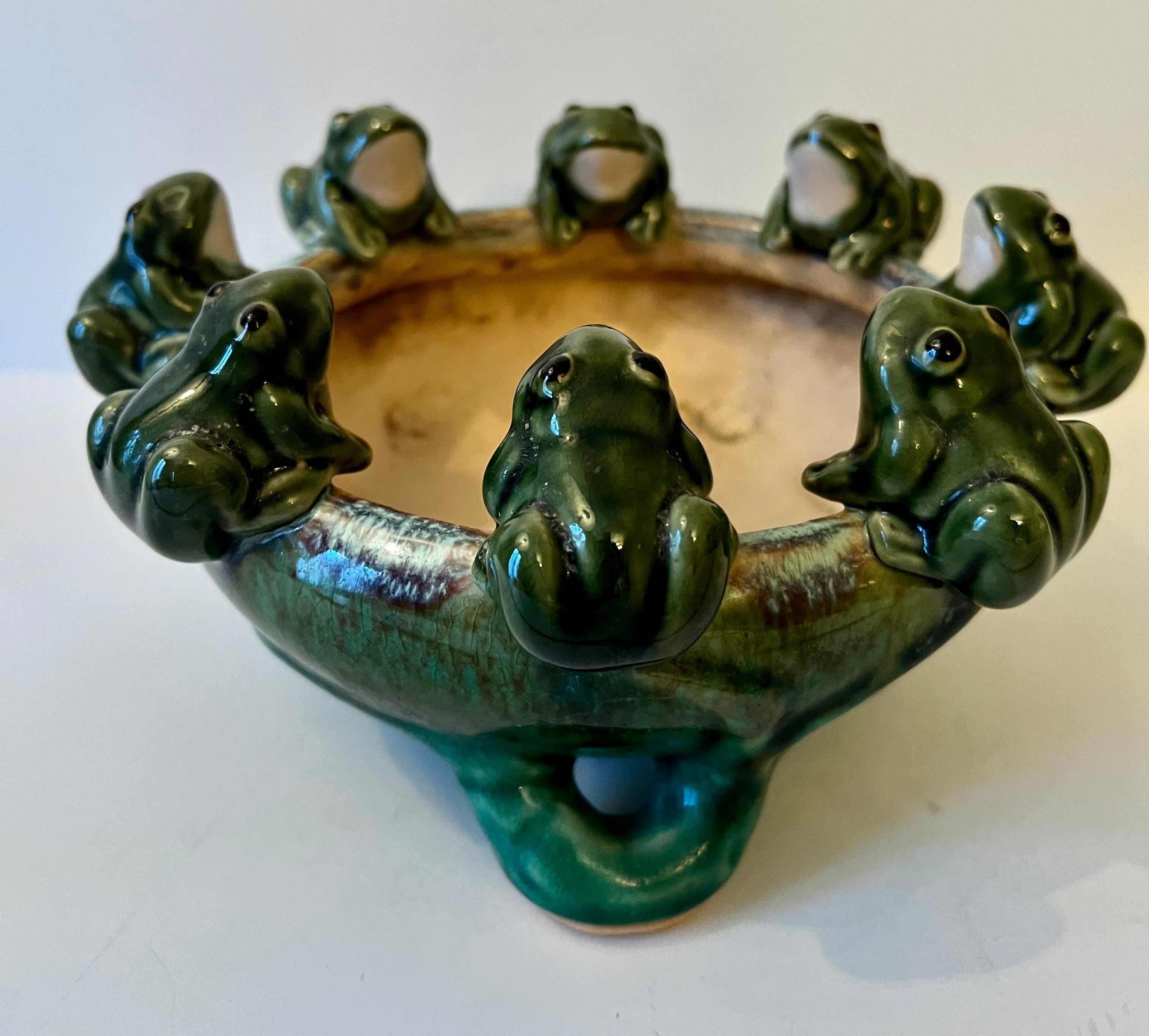 A delightful planter or jardiniere with frogs surrounding the opening.  The piece has small open feet.  Could be used for plants, arrangements or to float flowers.  Could be used as a candy dish as well.  A wonderful compliment to any garden or