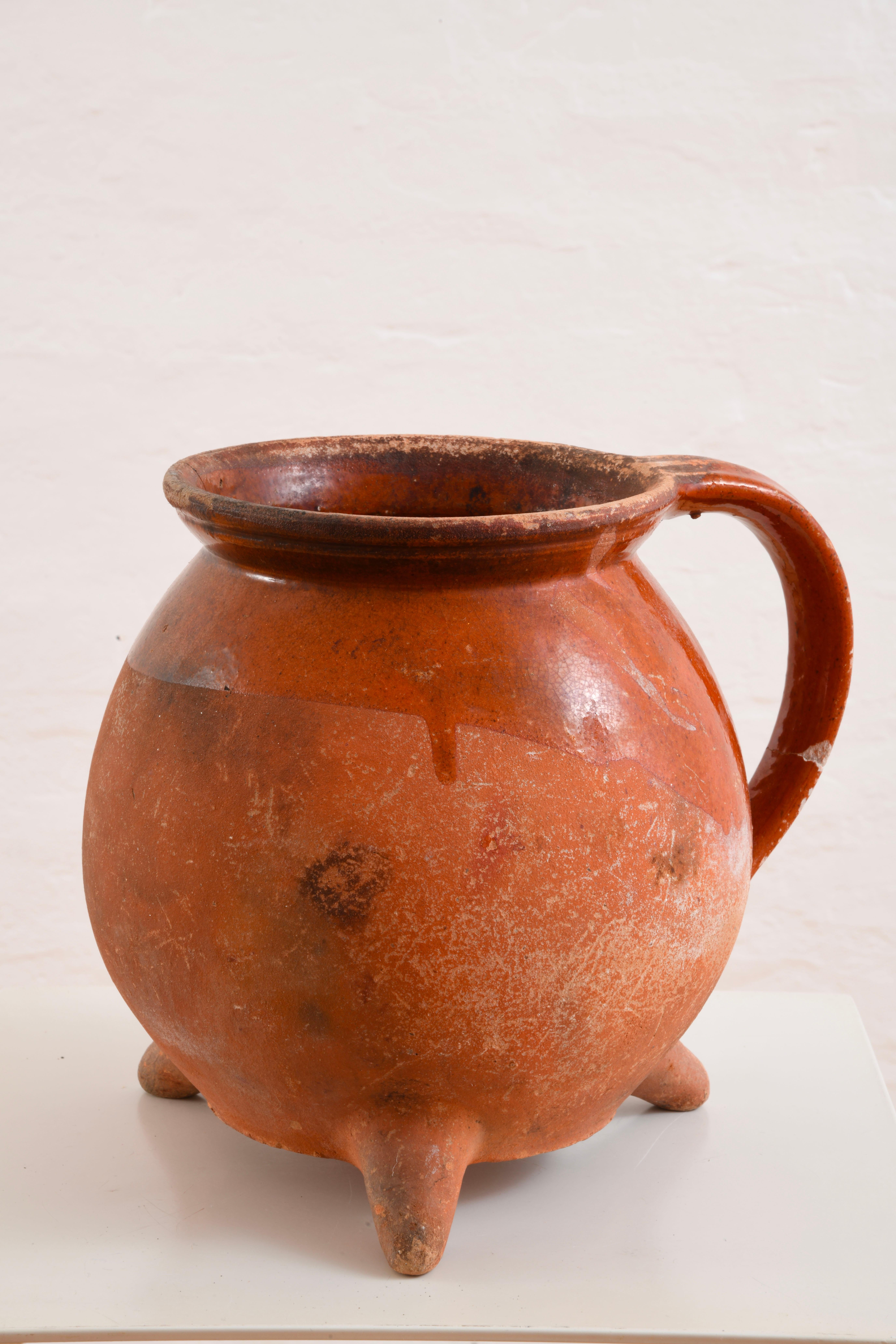 Brocca o vaso tripode in terracotta parzialmente smaltata, XIX secolo, Francia occidentale, regioni di Vandea e Poitou-Charente. Questo utensile veniva utilizzato principalmente per cucinare o riscaldare il cibo, grazie alla sua base a treppiede che