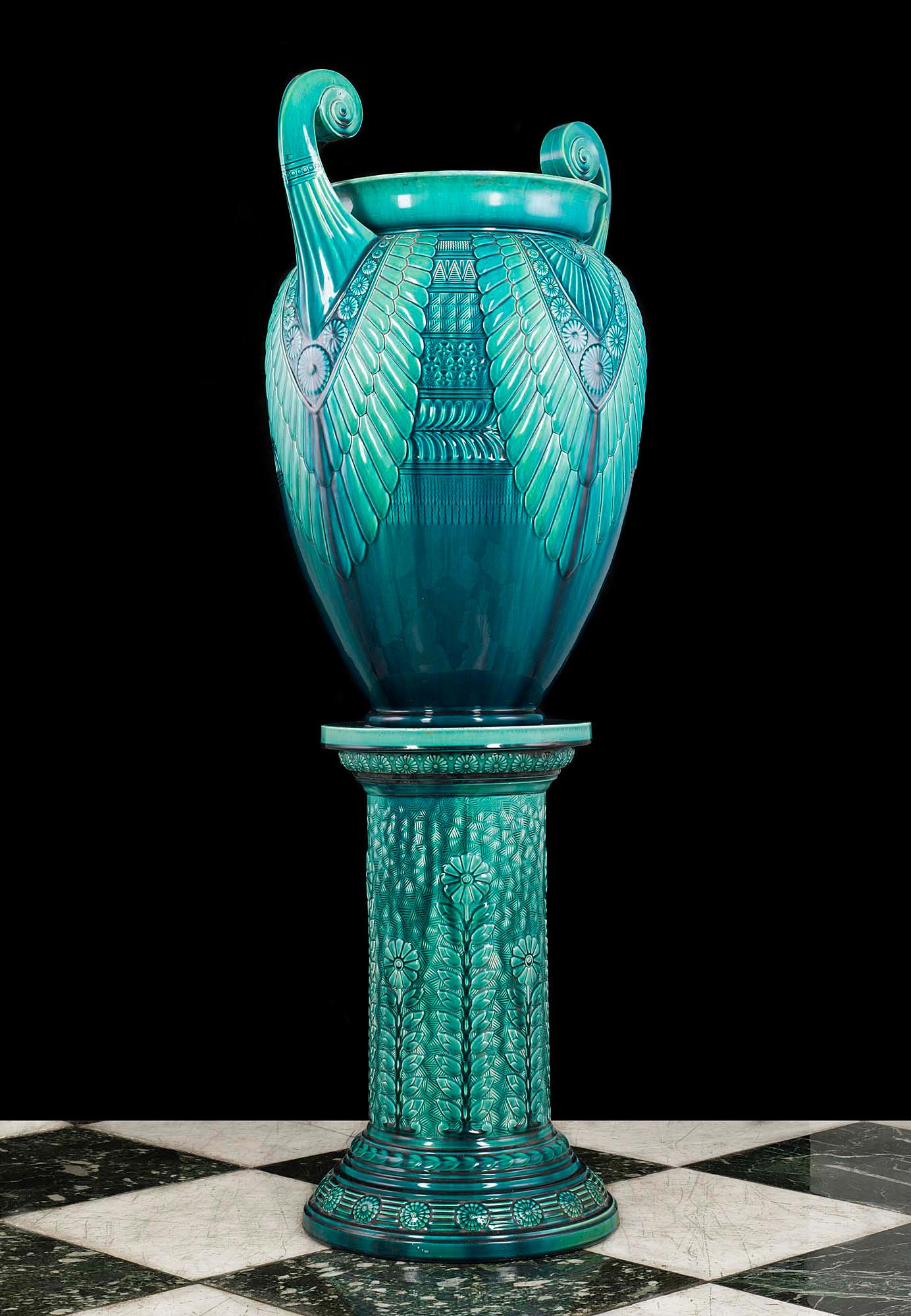 A large and rare glazed turquoise ceramic jardinière and Stand in the Egyptian manner designed by Christopher Dresser and made by the Linthorpe Art Pottery in Middlesbrough.

The jardinière is stamped with the makers name on the base, along with