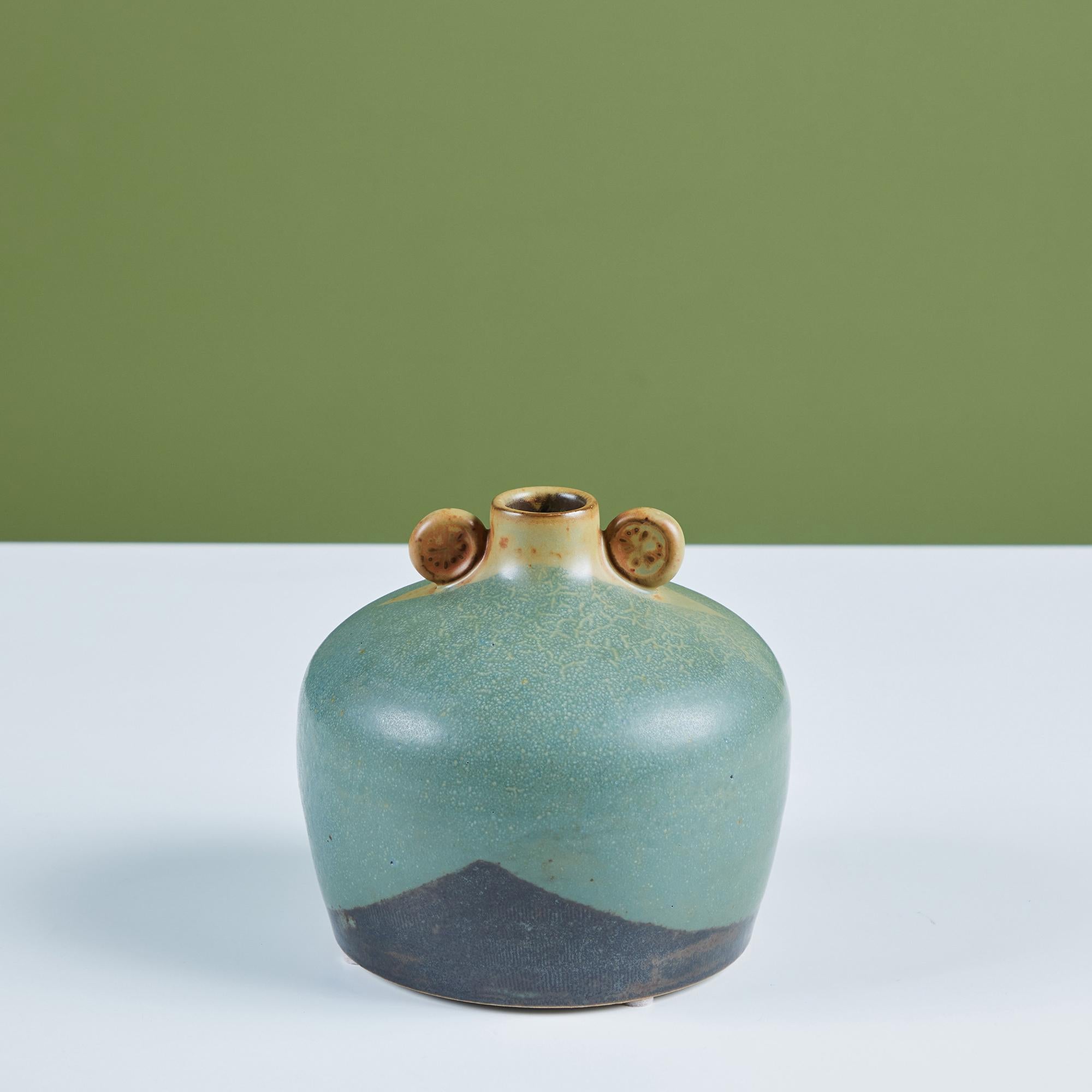 A rounded studio pottery bud vase with a two tone blue glaze and small rounded handles at the mouth of the vase.

Dimensions
5.5” diameter x 5.5” height; 1