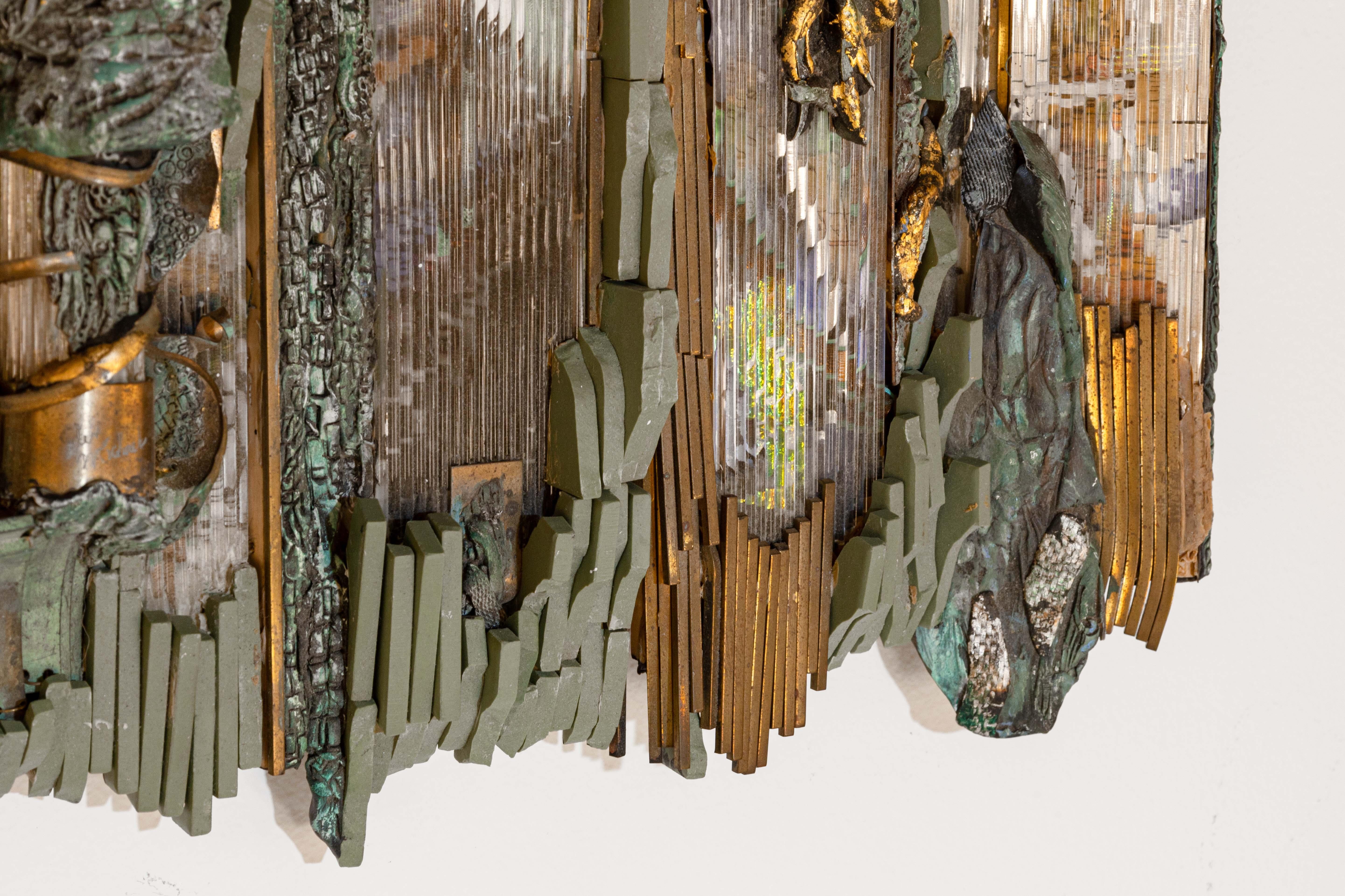 A contemporary mosaic wall sculpture assemblage by Cranbrook artist Glen Michaels. Etched signature bottom right. Circa 2000s. The center mosaic is made of bronze metals, glass, wood additions, and found objects. On the edge, the mosaic details are