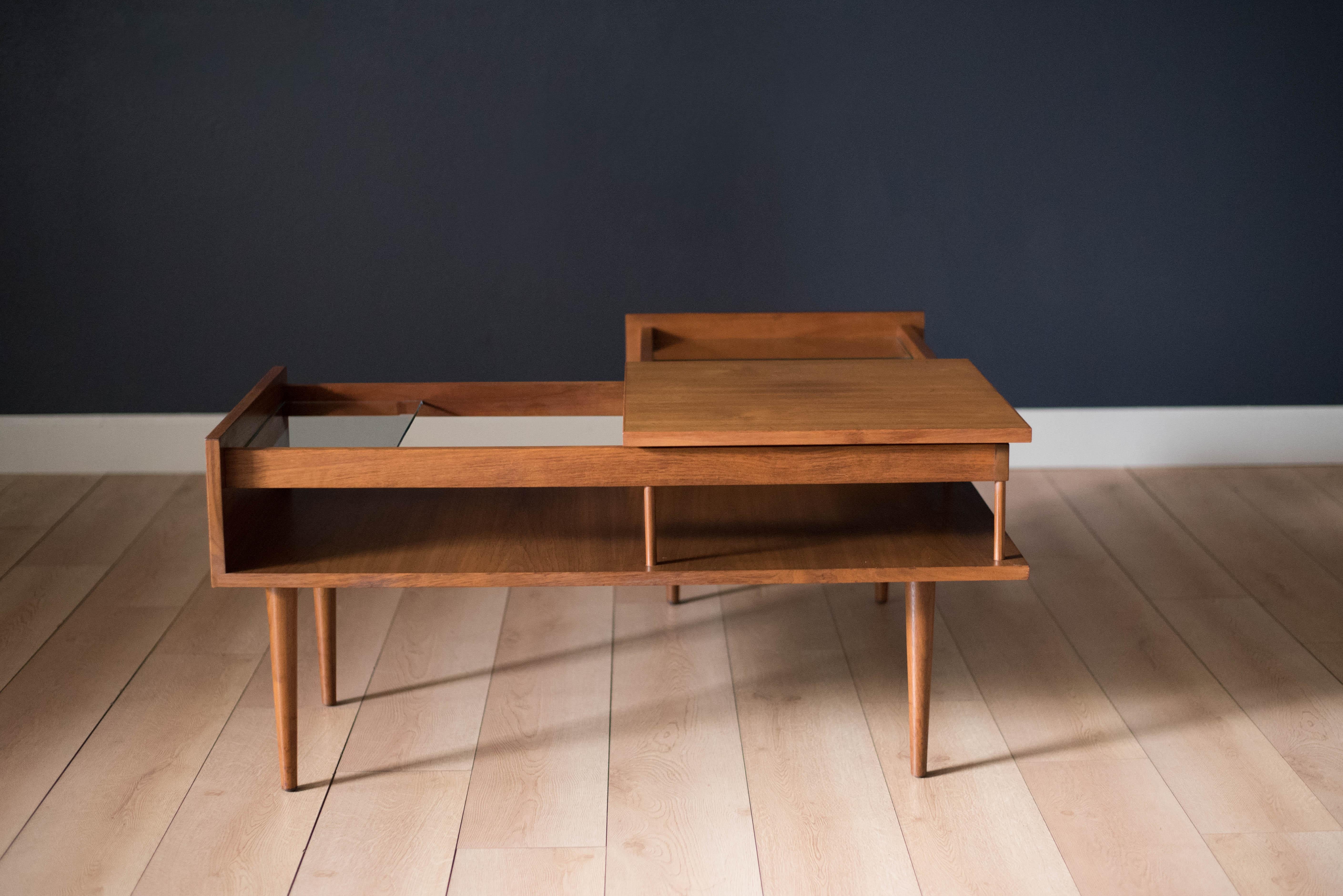 Mid century corner table designed by Milo Baughman for Glenn of California in walnut. This piece includes two glass shelves and a removable centre tabletop. Lower magazine shelf allows for extra storage. Displays well from all angles and fits as a