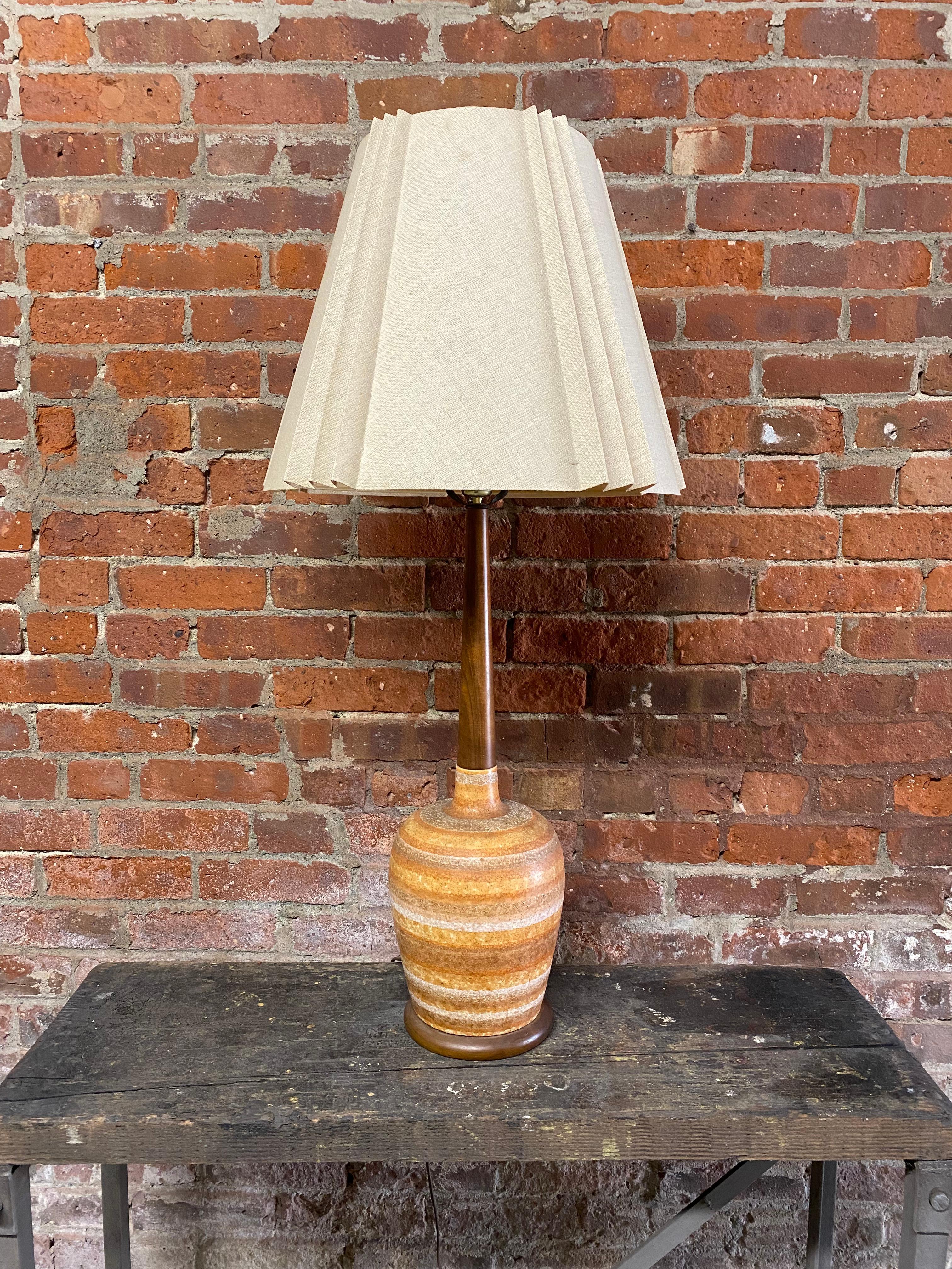 A nice combination of autumnal glazed ceramic and warm wood accent in the style of the Glidden Gulfstream line. Orange, rust, brown and off white glazes with a tapered walnut shaft and round base. Circa 1960. Good overall condition with no visible,