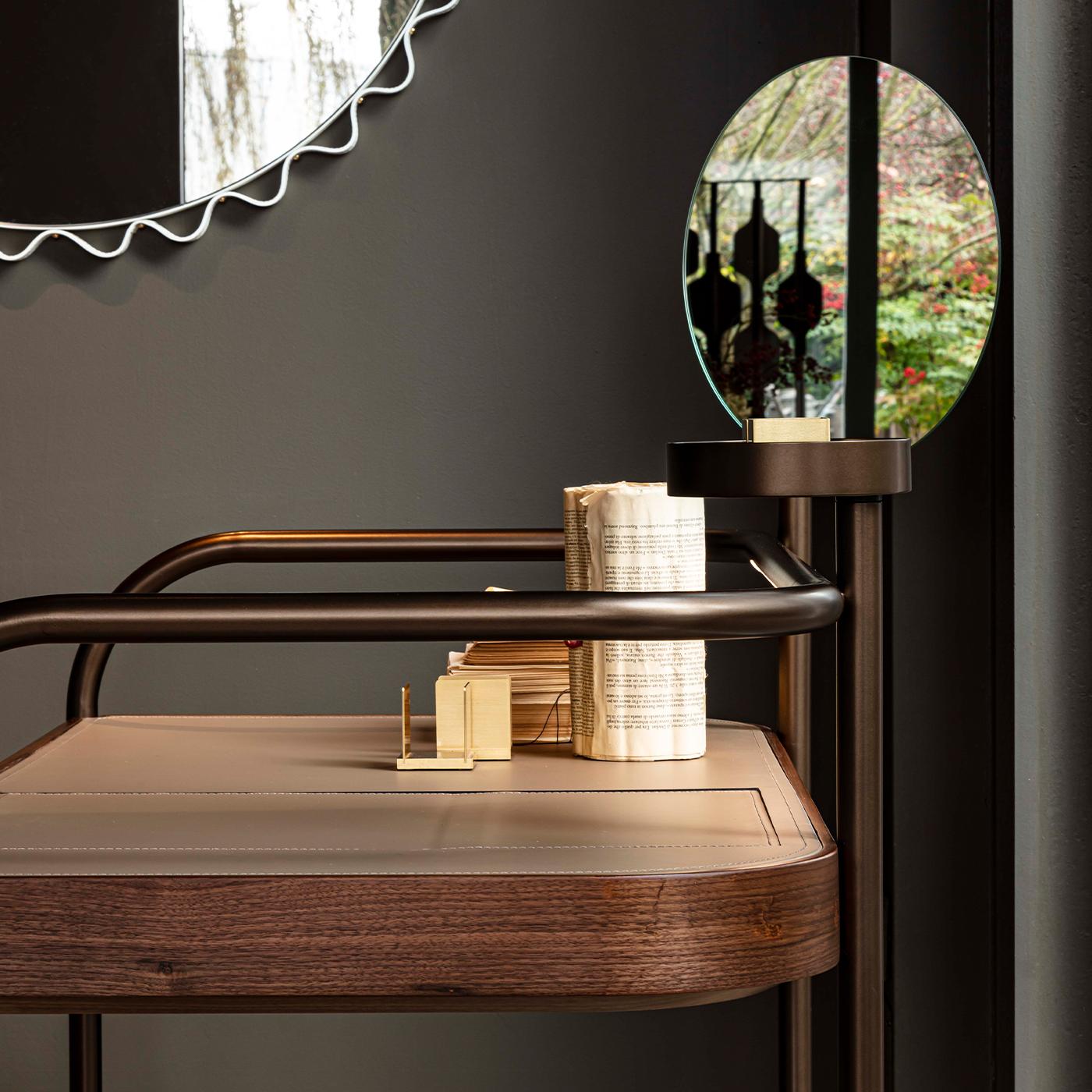 This stunning round mirror is marked by a clean and essential design enhanced by soft and sinuous lines that will bring a refined touch to any wall in a modern home. The graphite metal frame (available also in white, black, and bronze) is adorned