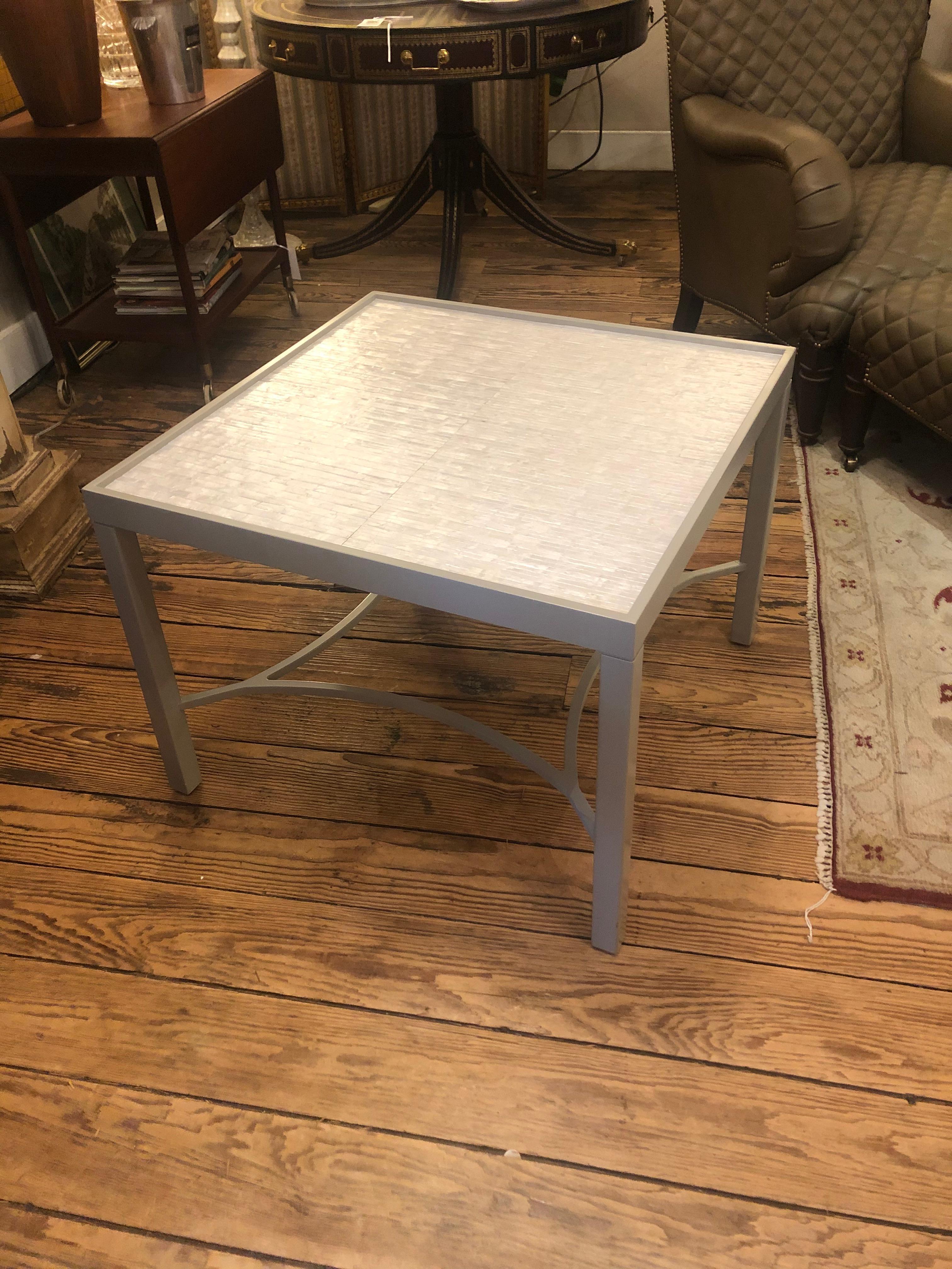 Sleek white and gray square cocktail table having recessed mosaic like faux mother of pearl or tessellated stone top and soft gray painted base with handsome stretcher underneath.