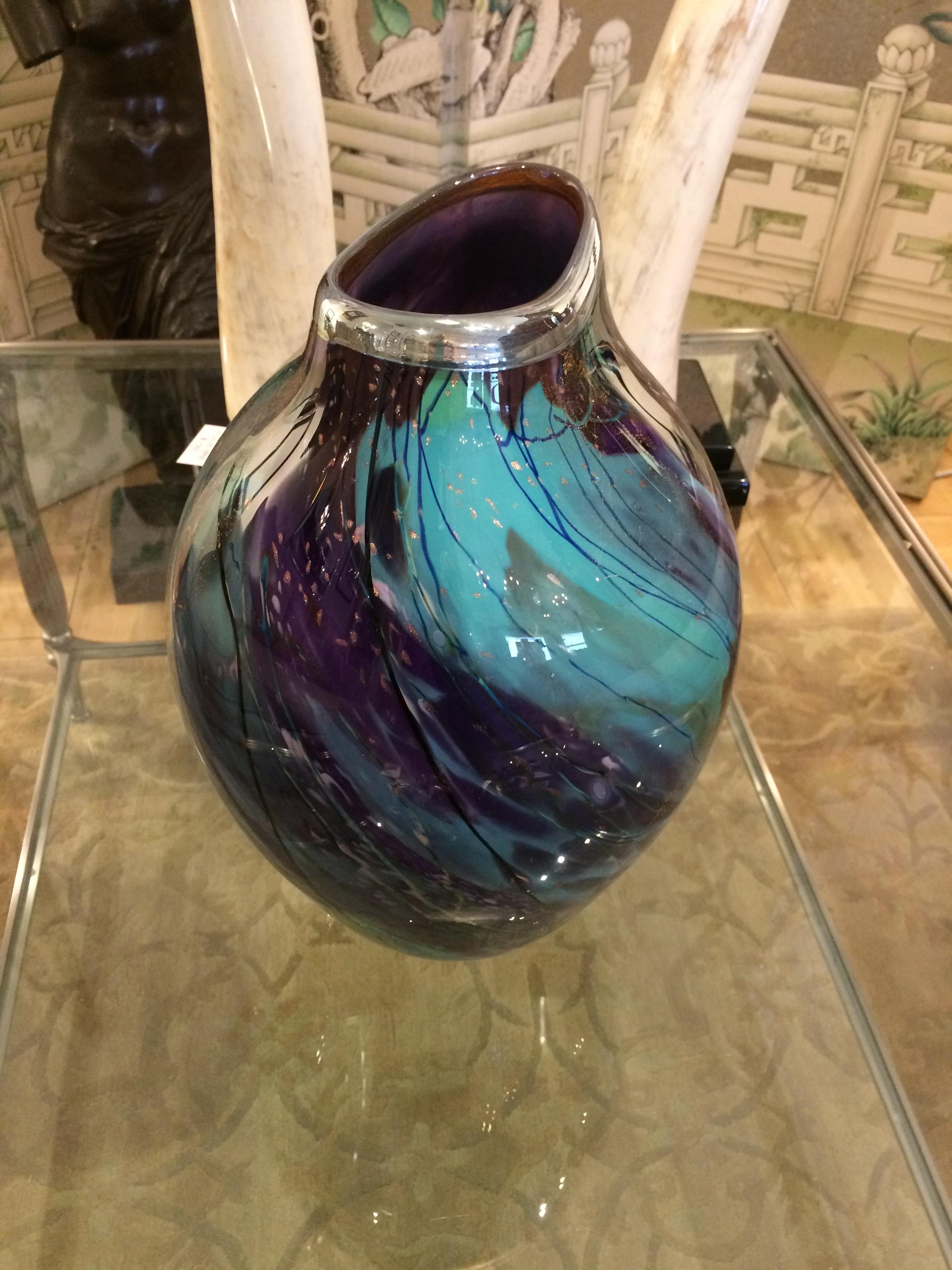 Magnificent handblown glass vase by artist Tim Lazer having a melange of gorgeous turquoises, purples and flecks of gold leaf in an abstract symphony, topped with a silver leaf rim around the 5.5 x 3.25 asymmetrical opening.