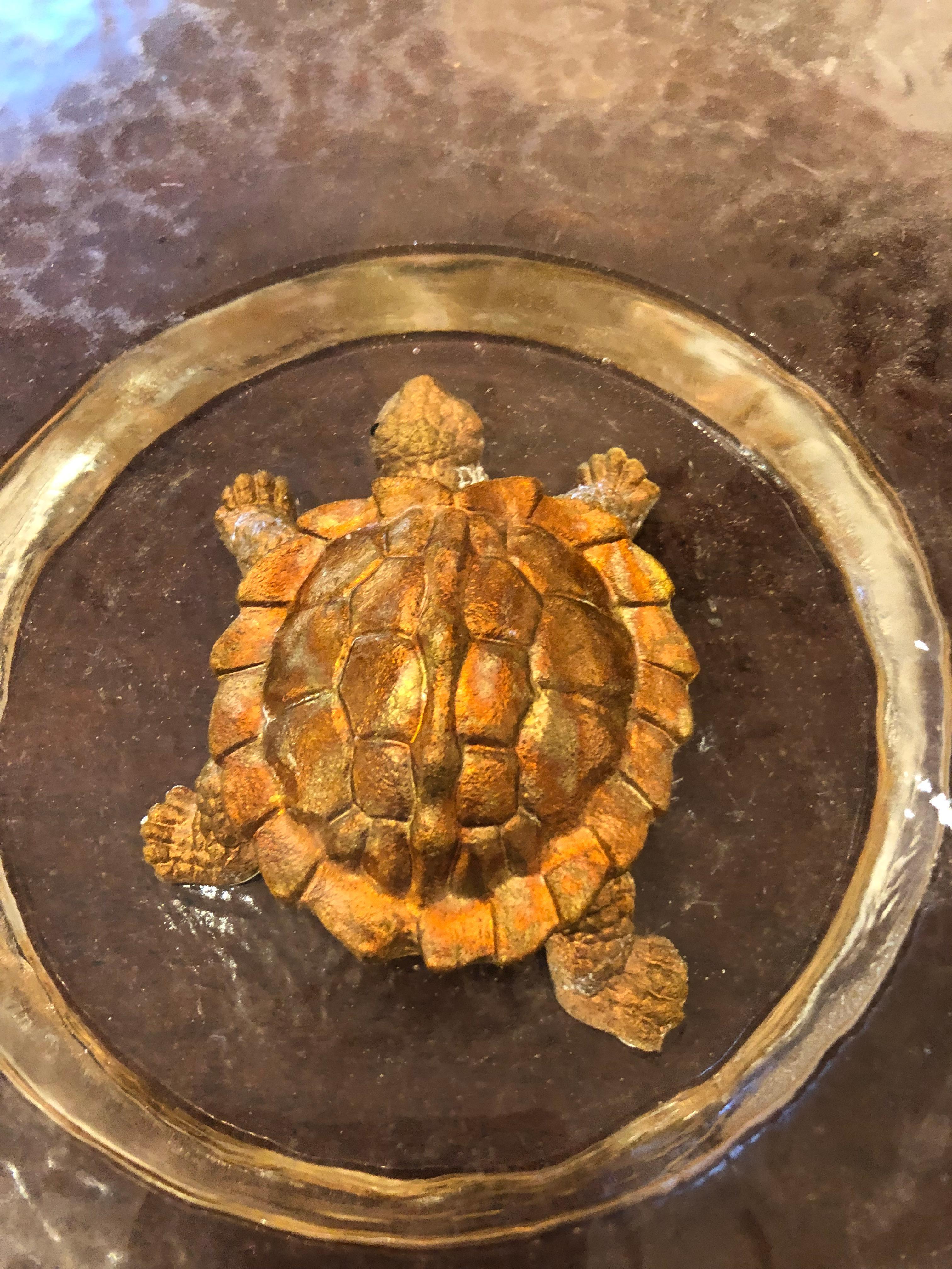 Swimming at the bottom of a glistening rippled glass bowl is a copper and gold leaf turtle. Signed on underside by artist. George Bucquet uses a process of pouring hot glass, thick and translucent, into handmade molds. His recognizable works are