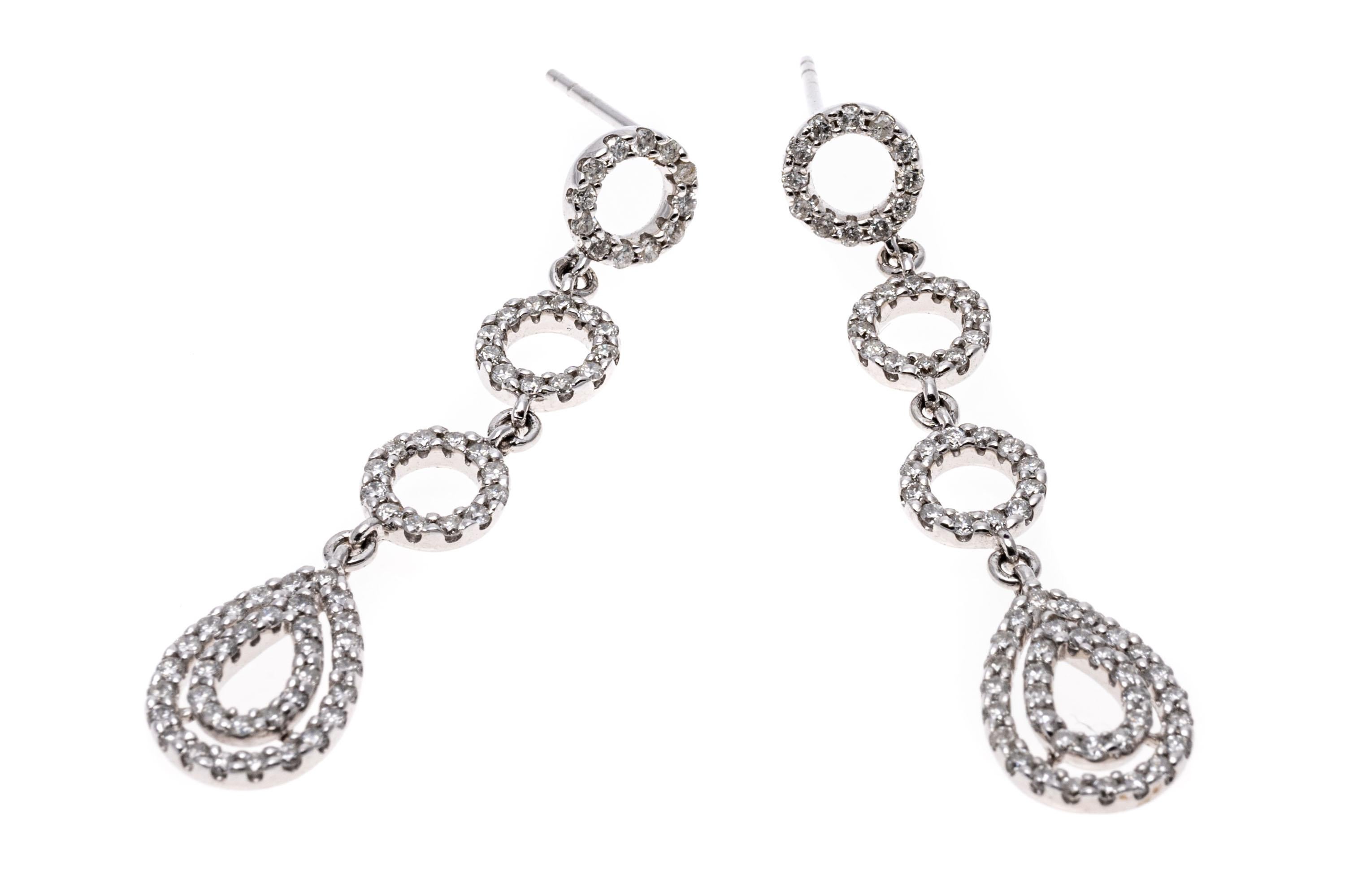 The glittering drop earrings are constructed of 14K white gold. Three circles set with diamonds leading down to a double teardrop form also set with diamonds. Earrings have post and clutch backings. Diamonds are approximately 1.05 TCW.
Marks: 14K