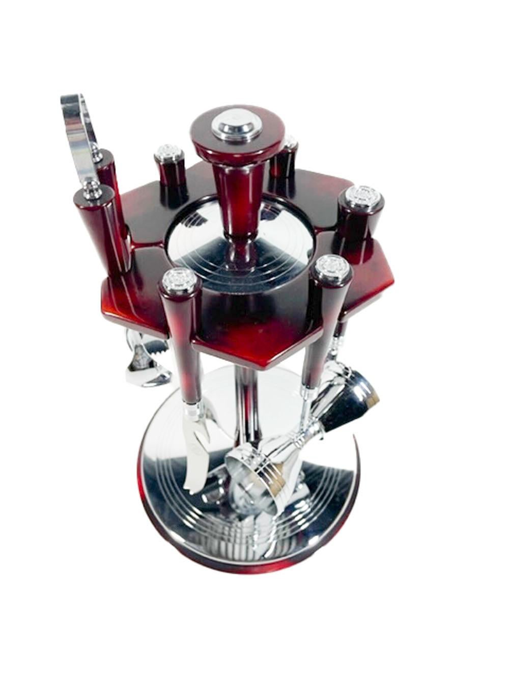 Six-piece bar tool set with revolving stand by Glo-Hill in red/black mottled faux tortoise Bakelite and chrome. A hexagonal Bakelite plate with cut-outs for the six tools is supported on a central column on a circular base.