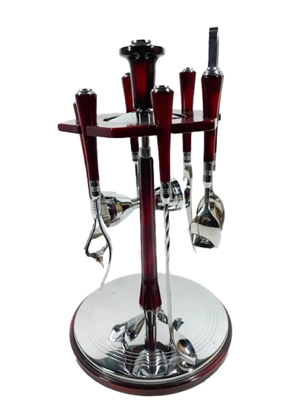 Six-piece bar tool set with revolving stand by Glo-Hill in red/black mottled faux tortoise Bakelite and chrome. A hexagonal Bakelite plate with cut-outs for the six tools is supported on a central column on a circular base.