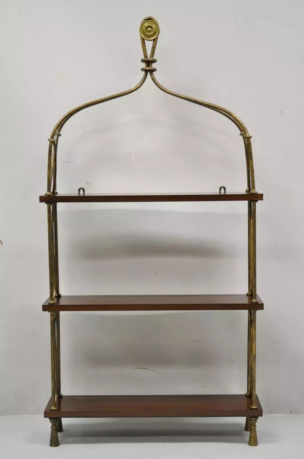 Global Views Scaffale espositivo da parete in ferro e legno con piede a nappe in stile francese. L'articolo è caratterizzato da una finitura dorata e distorta, 3 ripiani in legno massiccio con scanalature per le piastre, un medaglione in ottone,