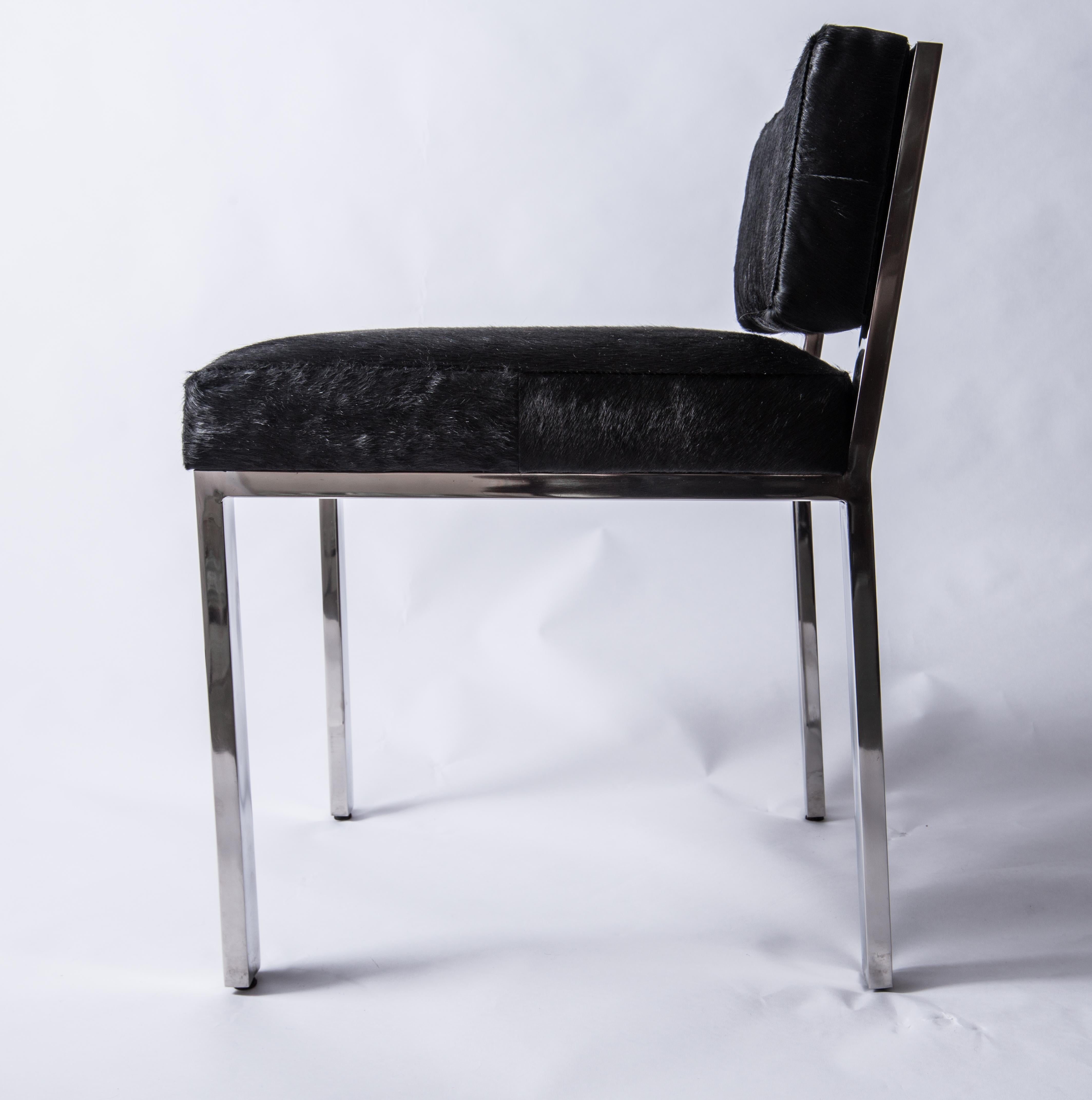 A cow hide stool/vanity seat by Global Views. Supported by a chrome structure. Back and seat are cushioned and upholstered in soft black horsehair.