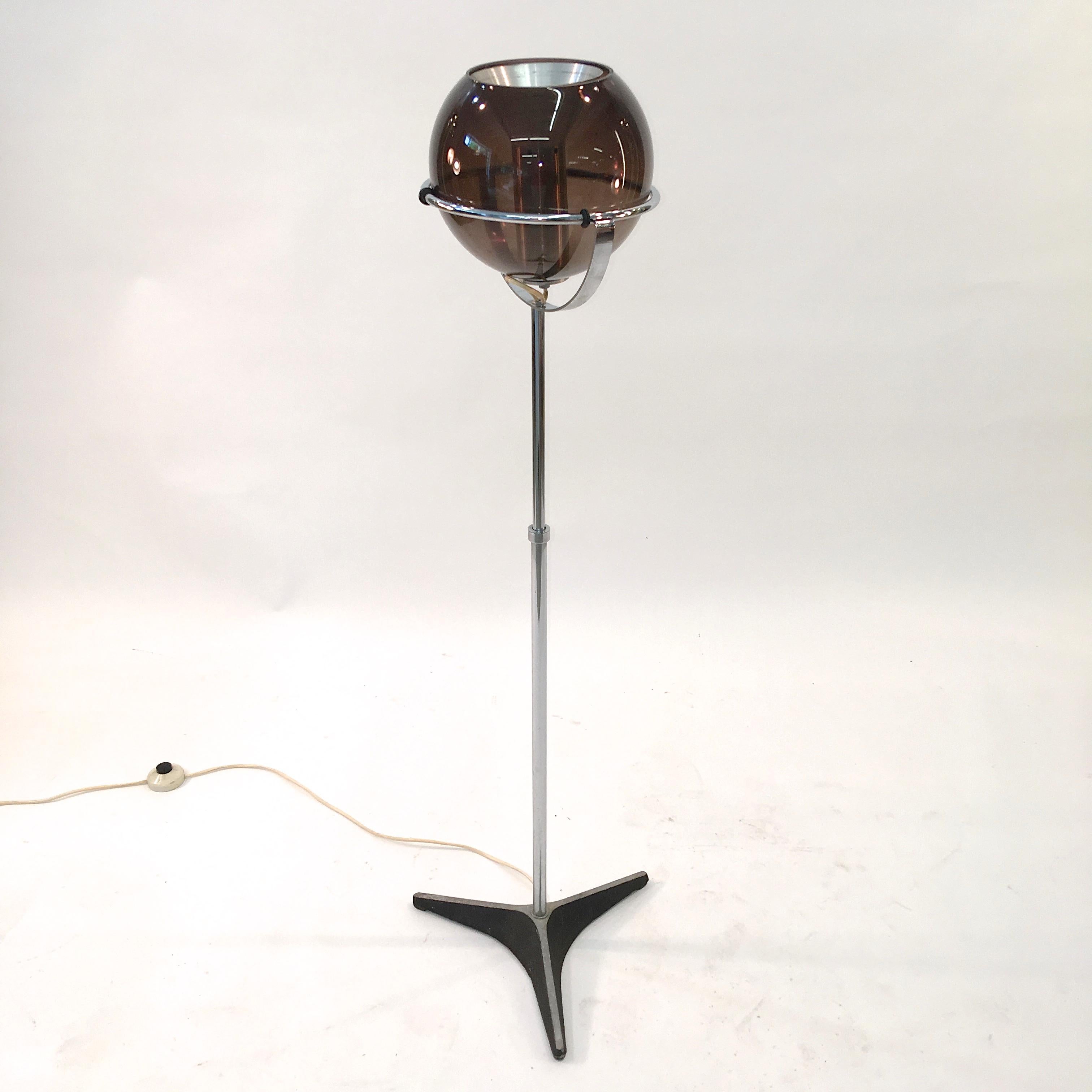 1960s smoked glass globe with an internal spun aluminum cone reflector, supported by a chrome structure on adjustable stem and black painted tri-star base.
This floor lamp is part of RAAK's highly successful 1960s Globe series by Frank