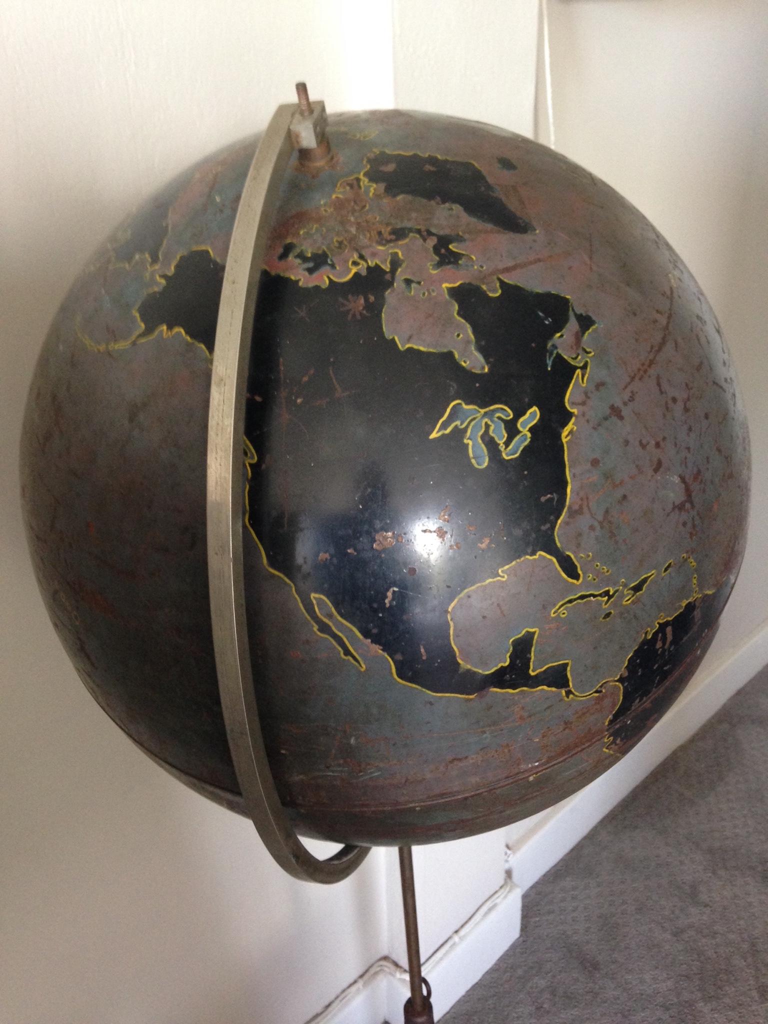 Globe of steel with heavy, cast iron base by Denoyer Geppert, circa 1920s. Used as aviation training tool by the military, hence lack of identifying information on the land masses. Beautifully worn patina of browns and blacks mounted on adjustable