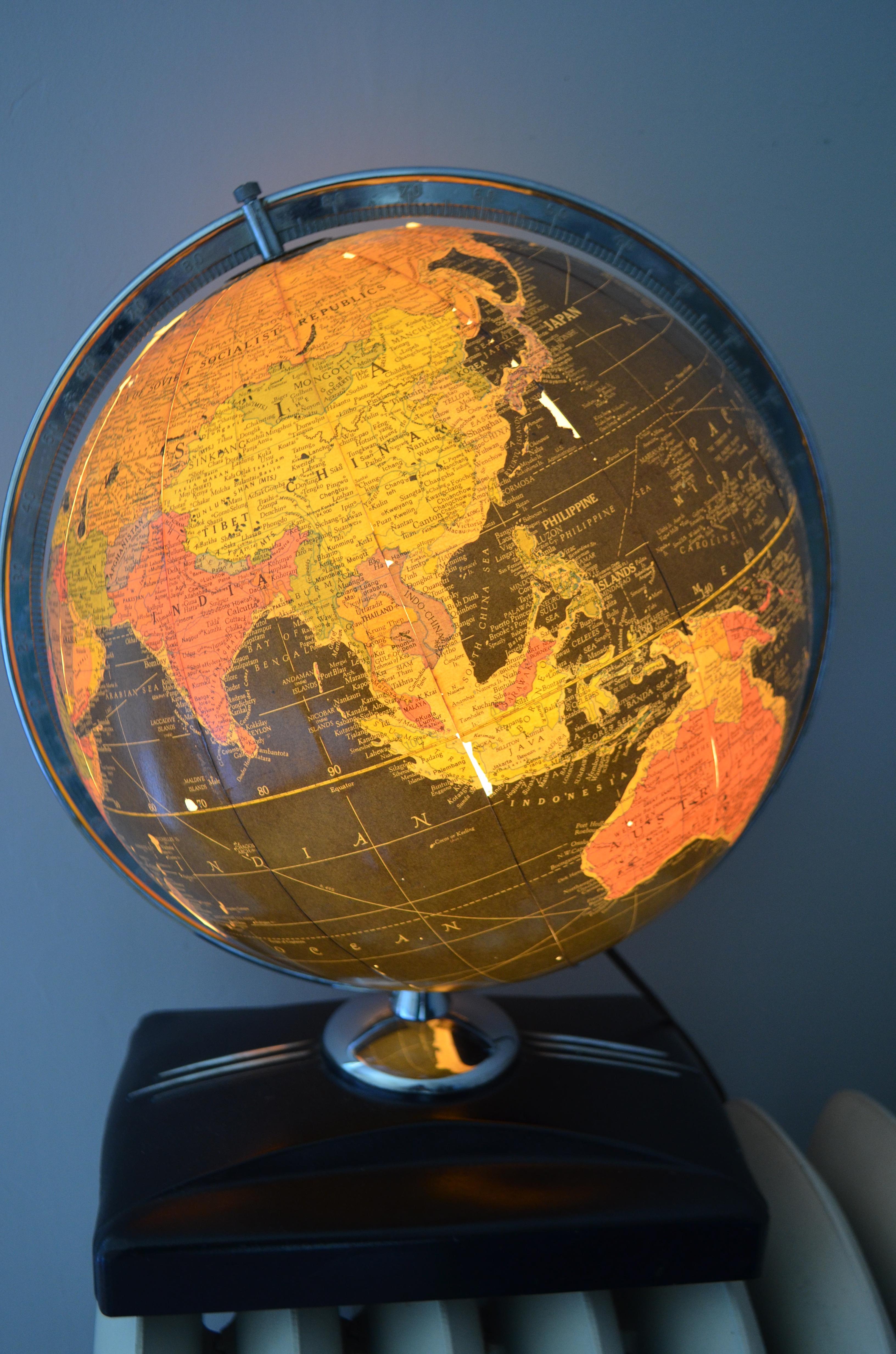 Art Deco era globe on book-slotted stand. Lights up with the click of a switch. Dramatic black background beneath a warm diffusion of colors. Love the sleek silver aluminum mounting arc. As we've been encompassed by the digital era, tangible,